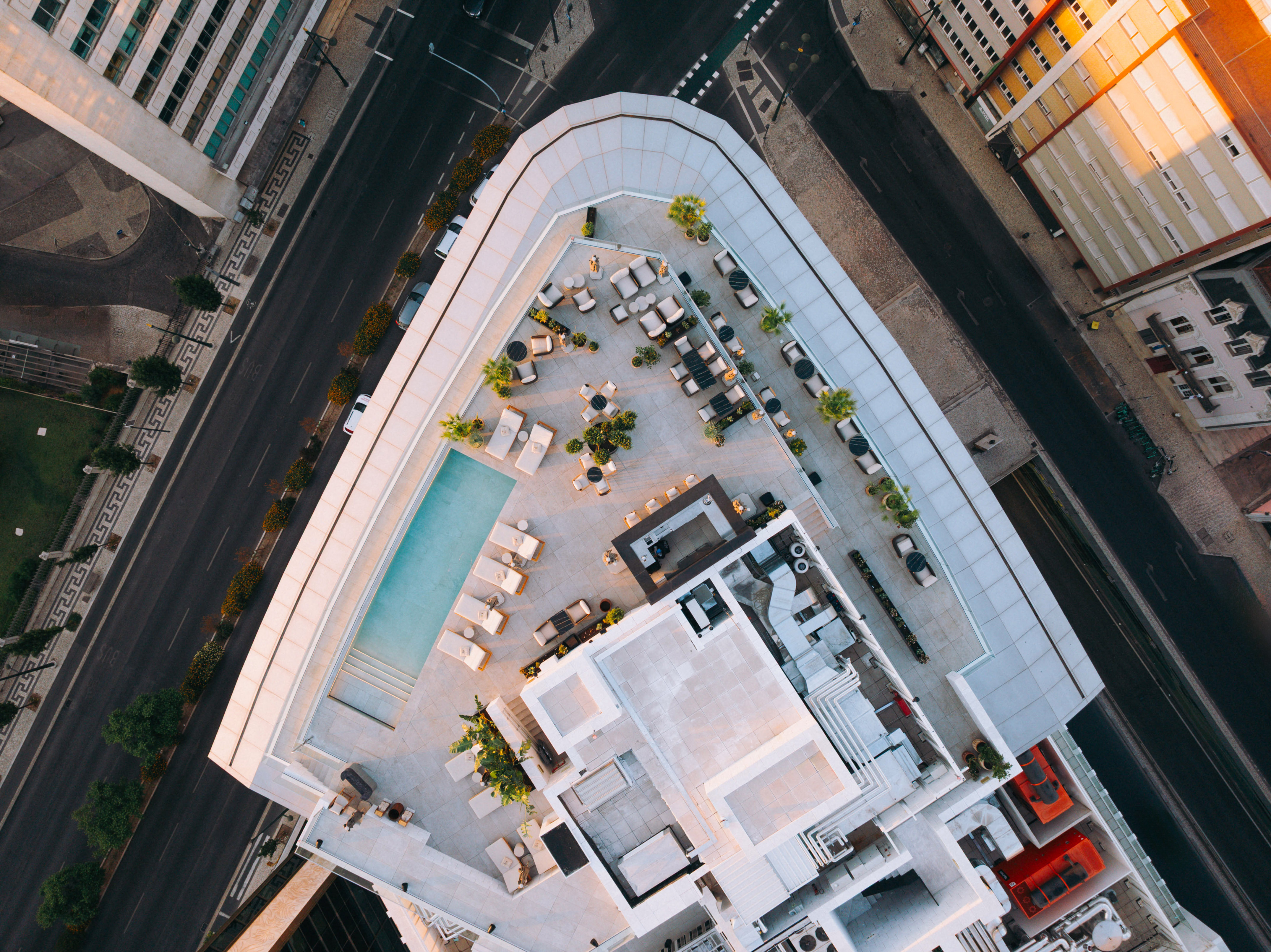 Aerial view of modern city rooftop terrace with pool and lounge areas.