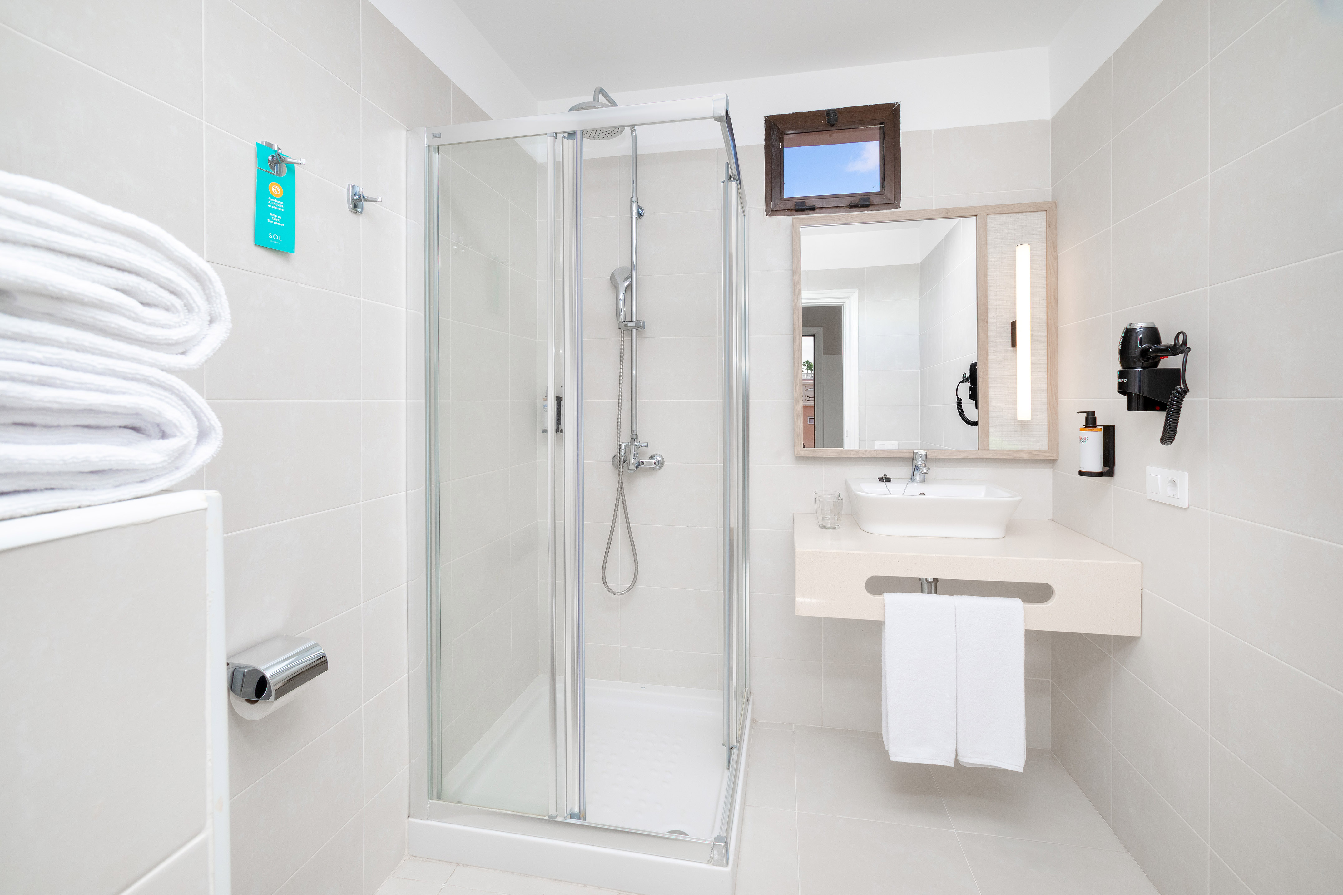 Modern hotel bathroom with walk-in shower, vanity, mirror, and white towels.