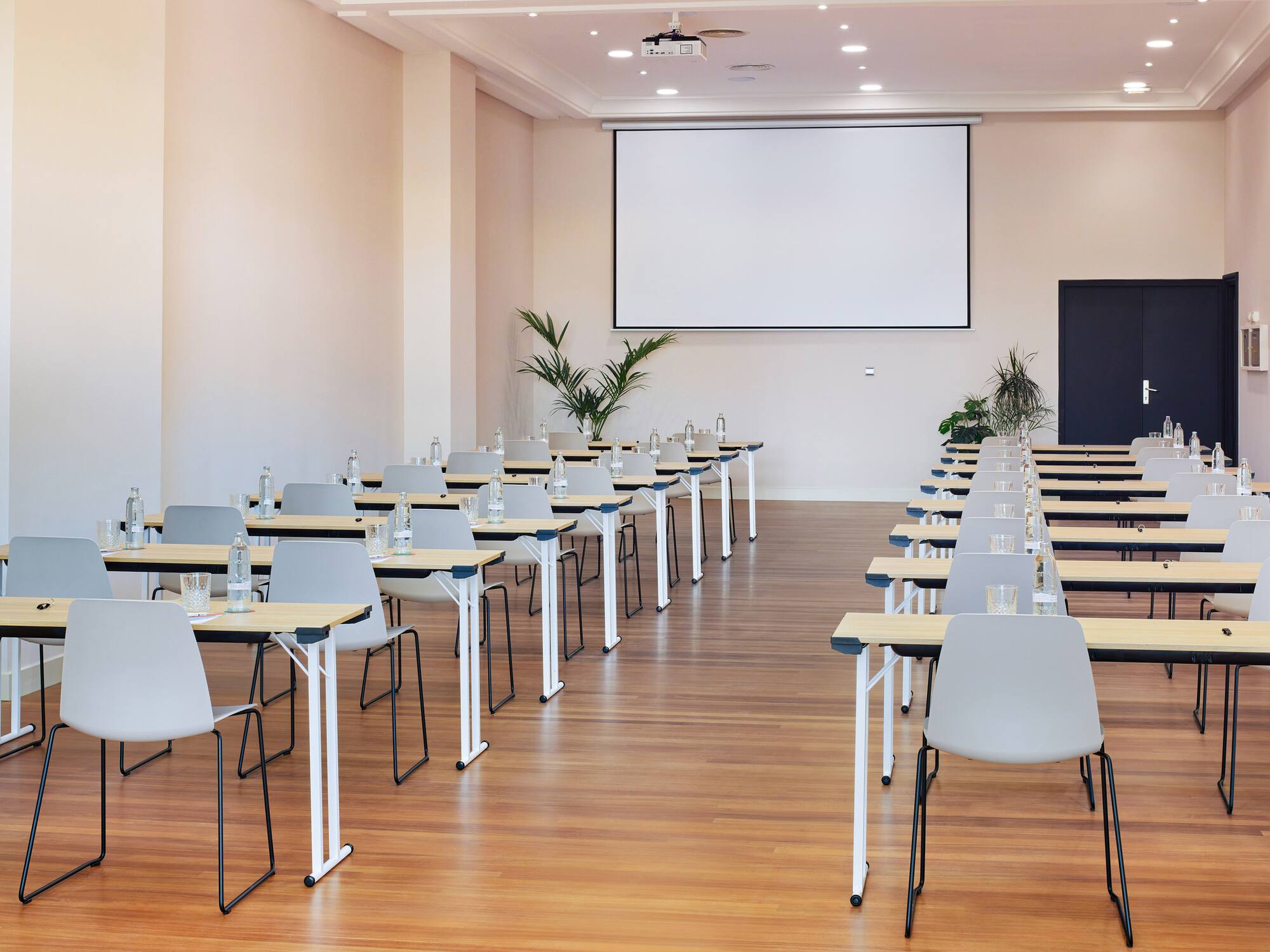Sala de conferencias equipada con proyector, mesas y sillas.
