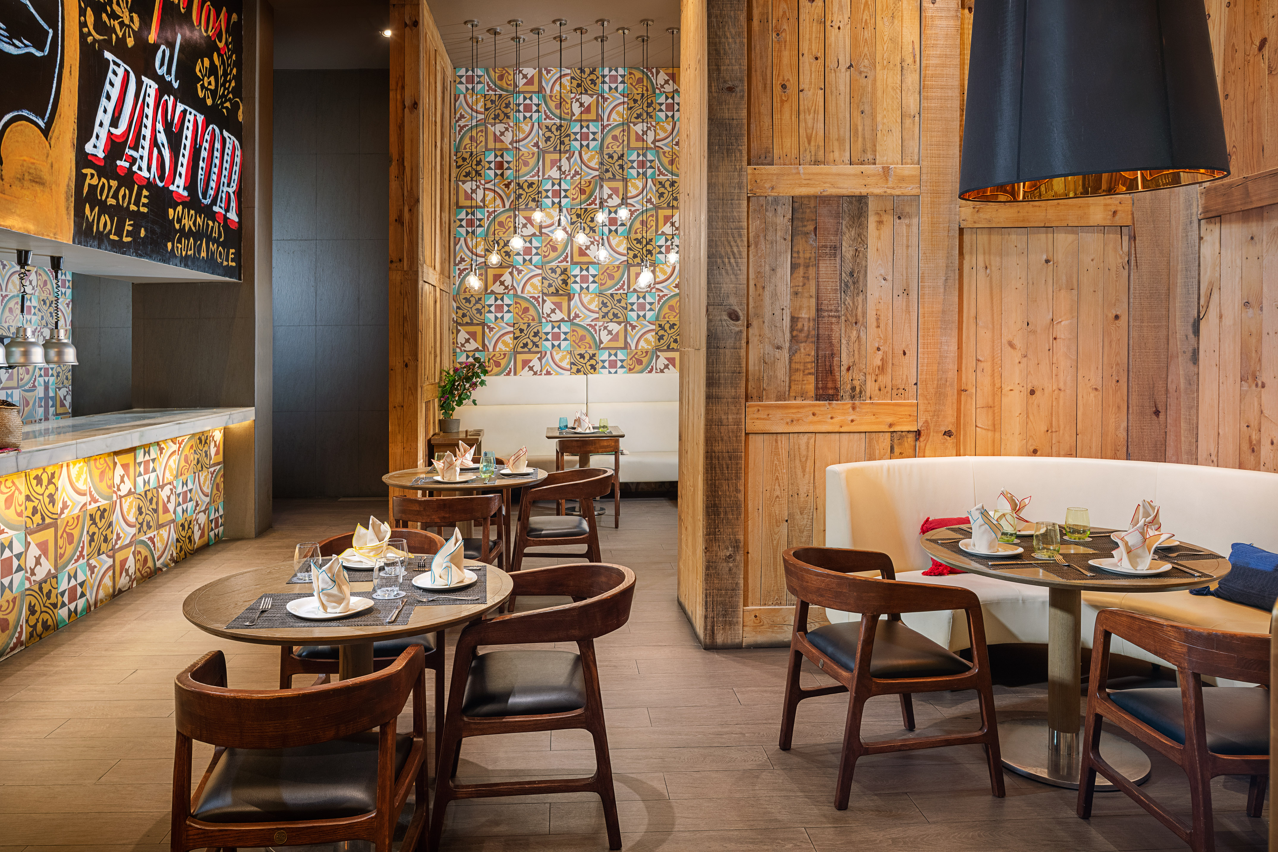 Mexican dining room with wooden decor, colorful patterned tiles, and bar.