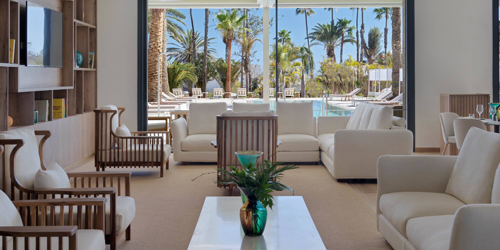 a room with white furniture and a pool in the background
