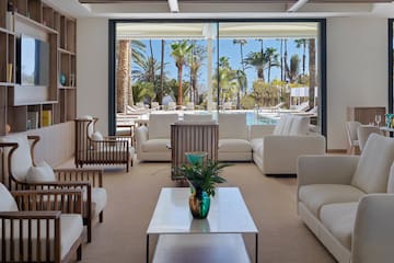 a room with white furniture and a pool in the background