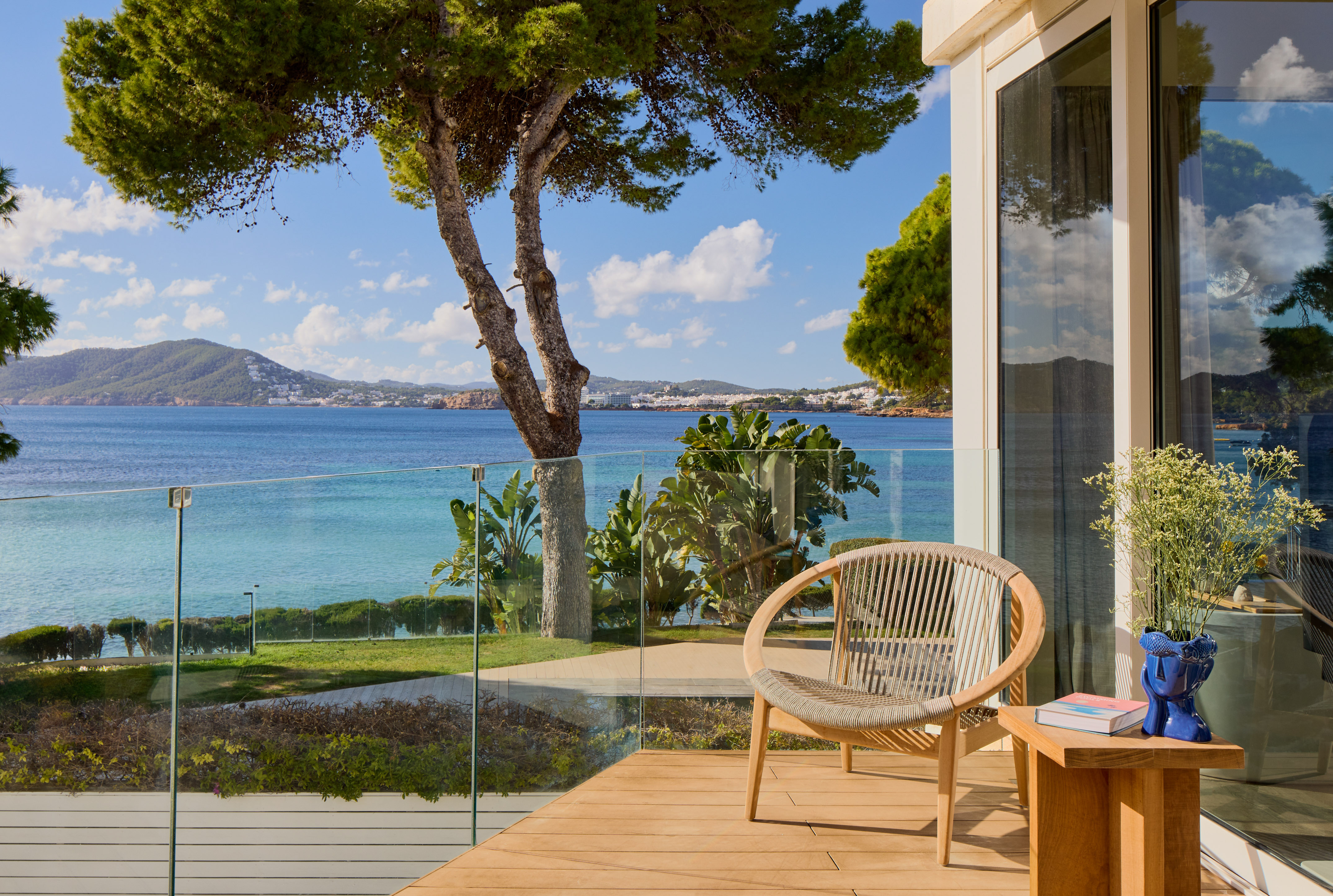 Balcony with wooden deck, modern chair, and Mediterranean sea view.