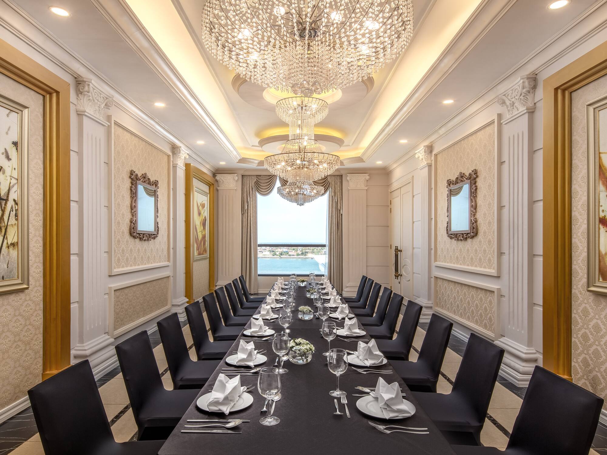 a long table with black chairs and plates and glasses