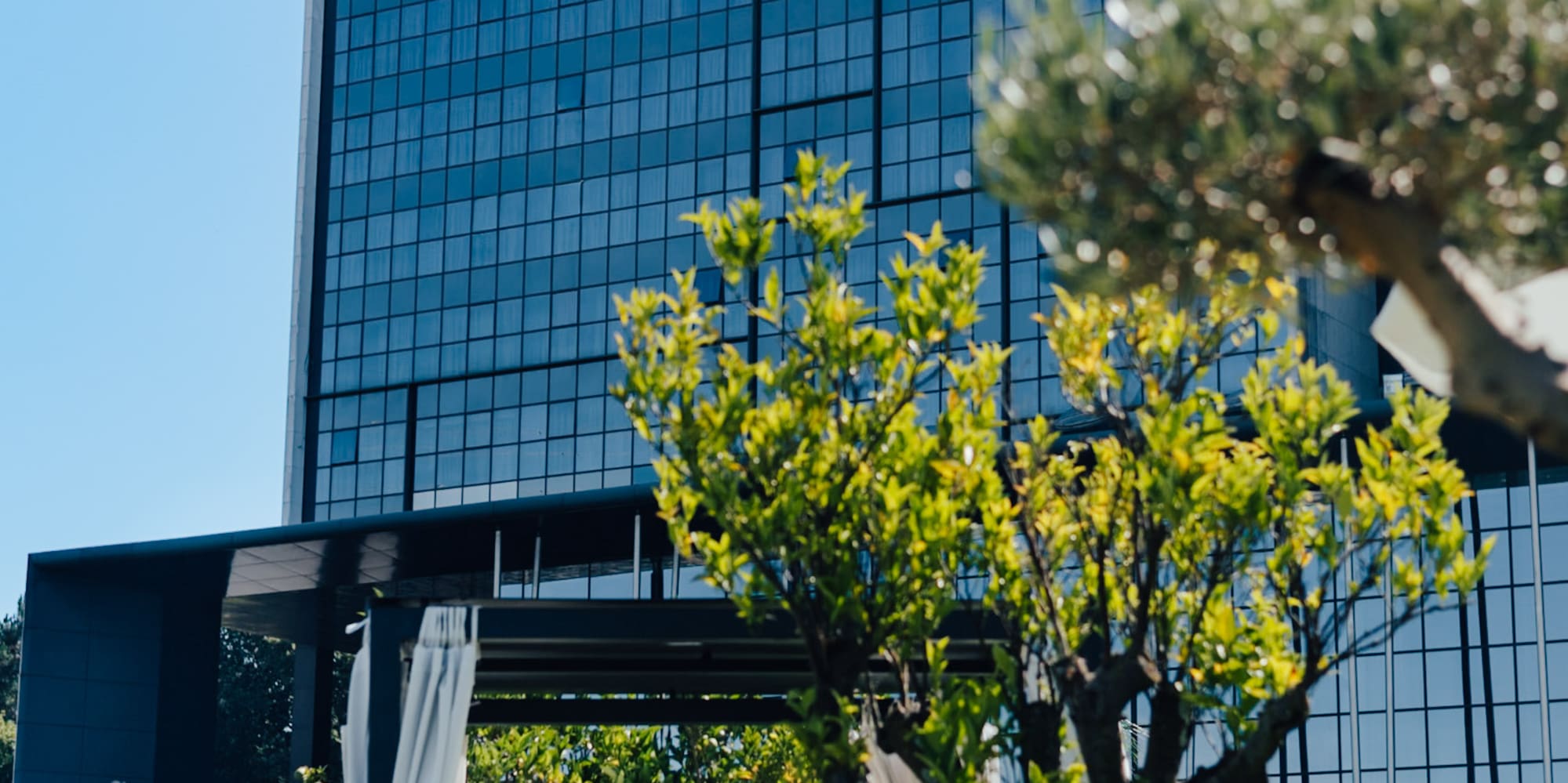 Hotel Meliã Braga with modern glass exterior and sunny outdoor lounge area.