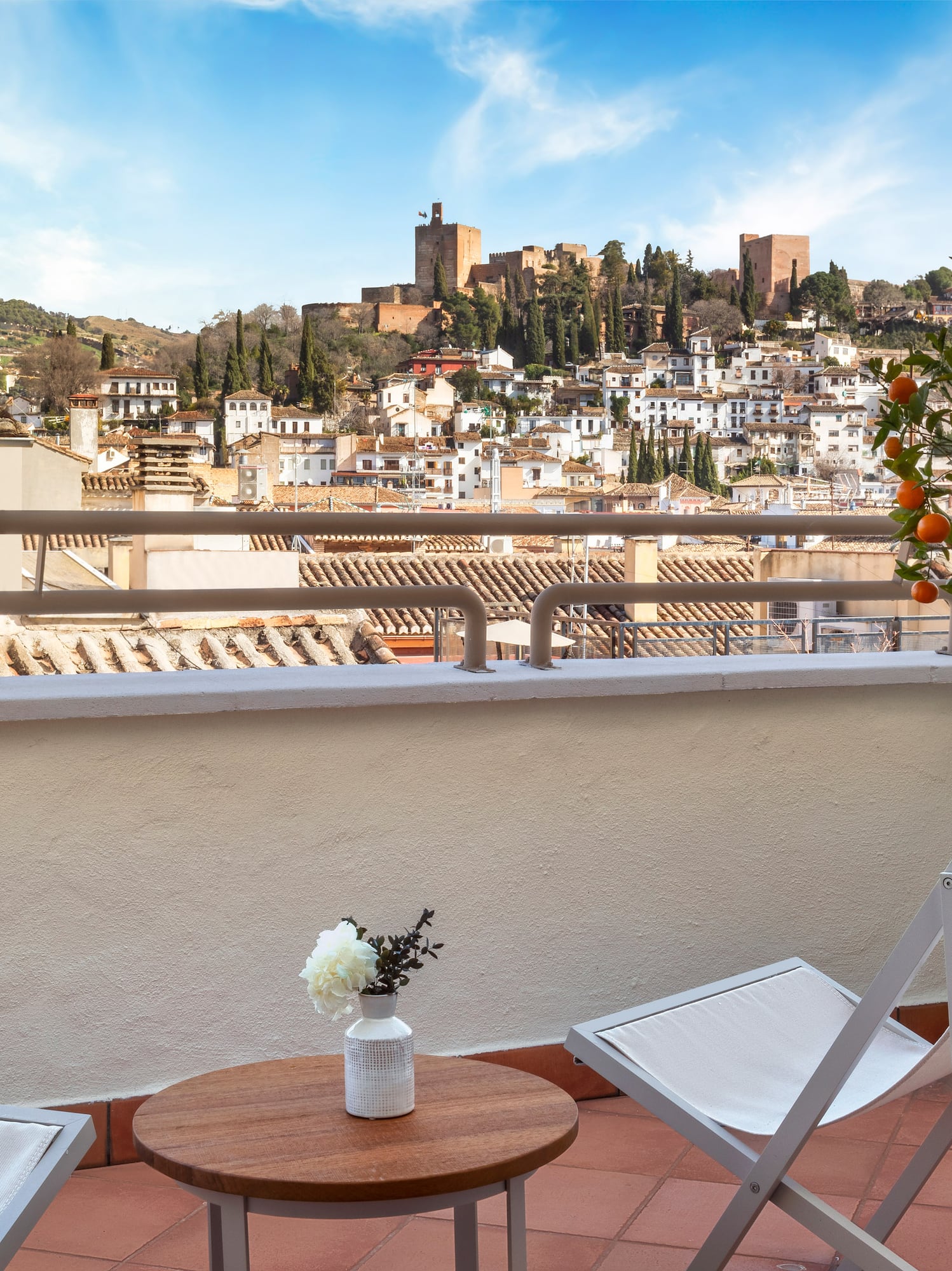 a chair and table on a balcony with a city in the background