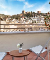 a chair and table on a balcony with a city in the background