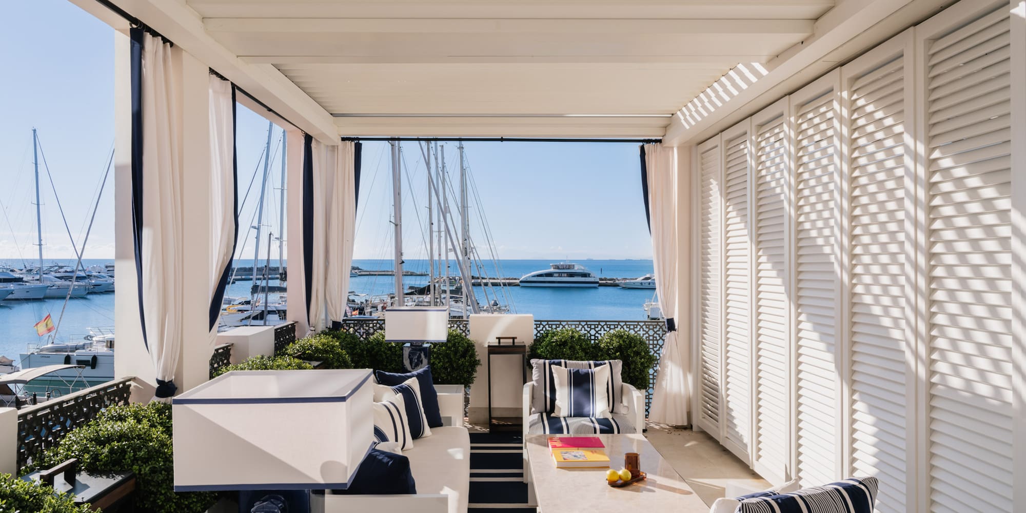 a patio with a table and chairs and a boat in the water