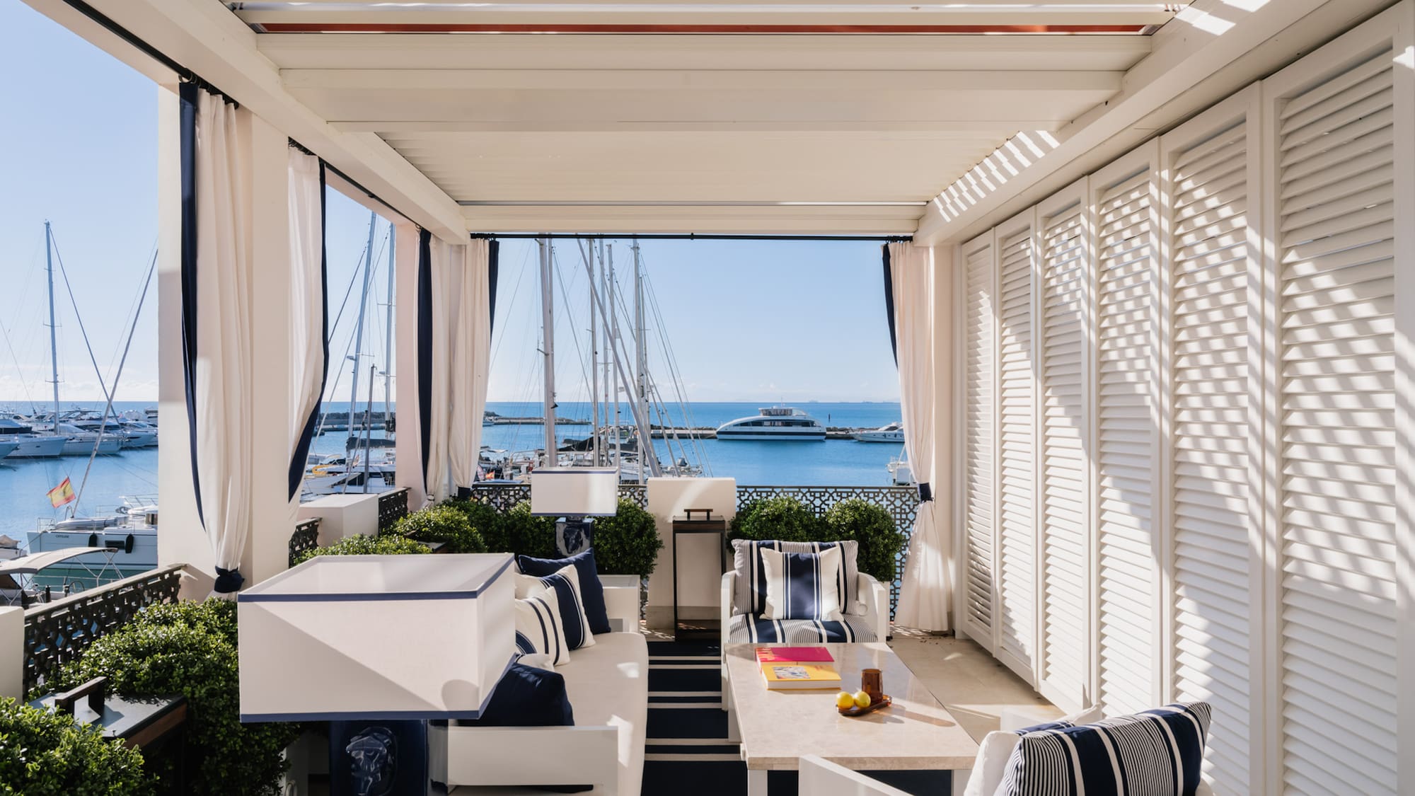a patio with a table and chairs and a boat in the water