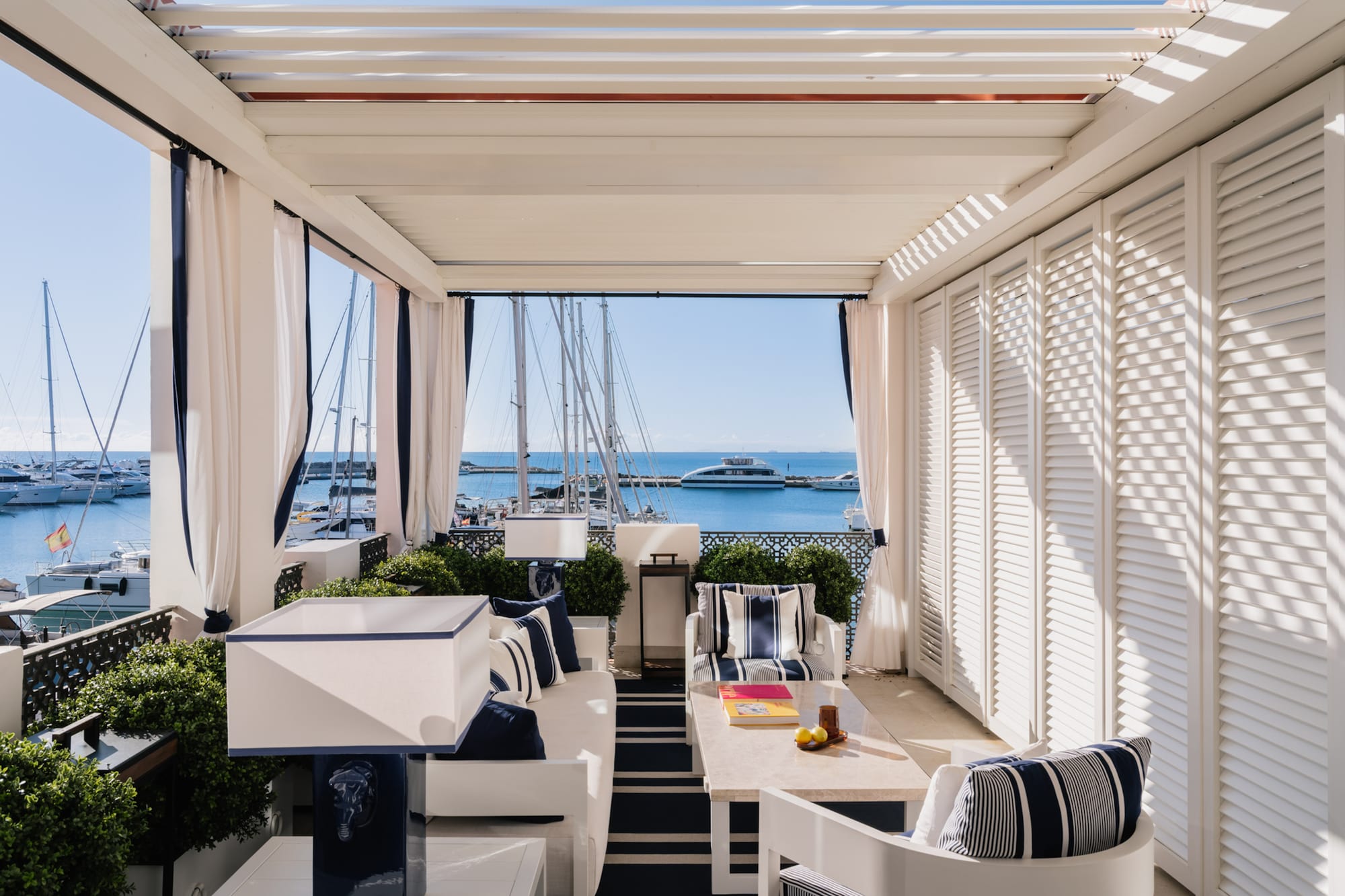 a patio with a table and chairs and a boat in the water