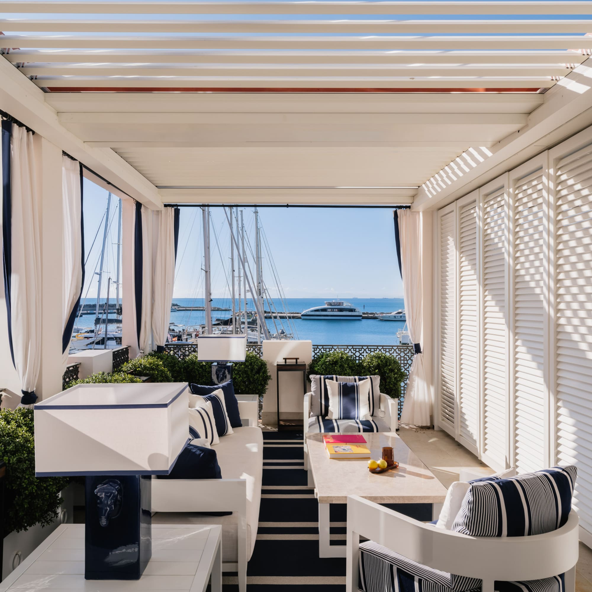 a patio with a table and chairs and a boat in the water