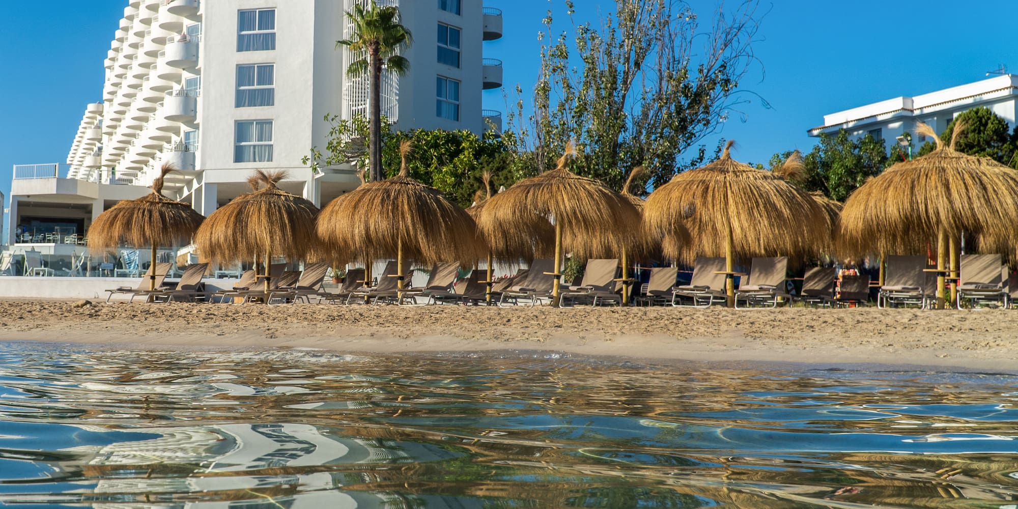 a beach with straw umbrellas and chairs on the beach