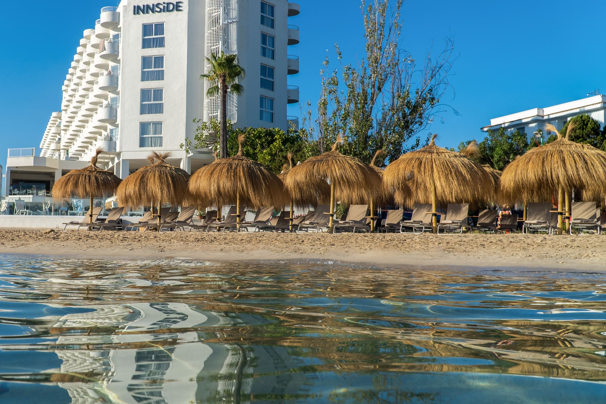 Innside beach resort hotel, straw umbrellas, lounge chairs, ocean reflections.