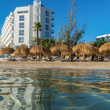 a beach with straw umbrellas and chairs on the beach