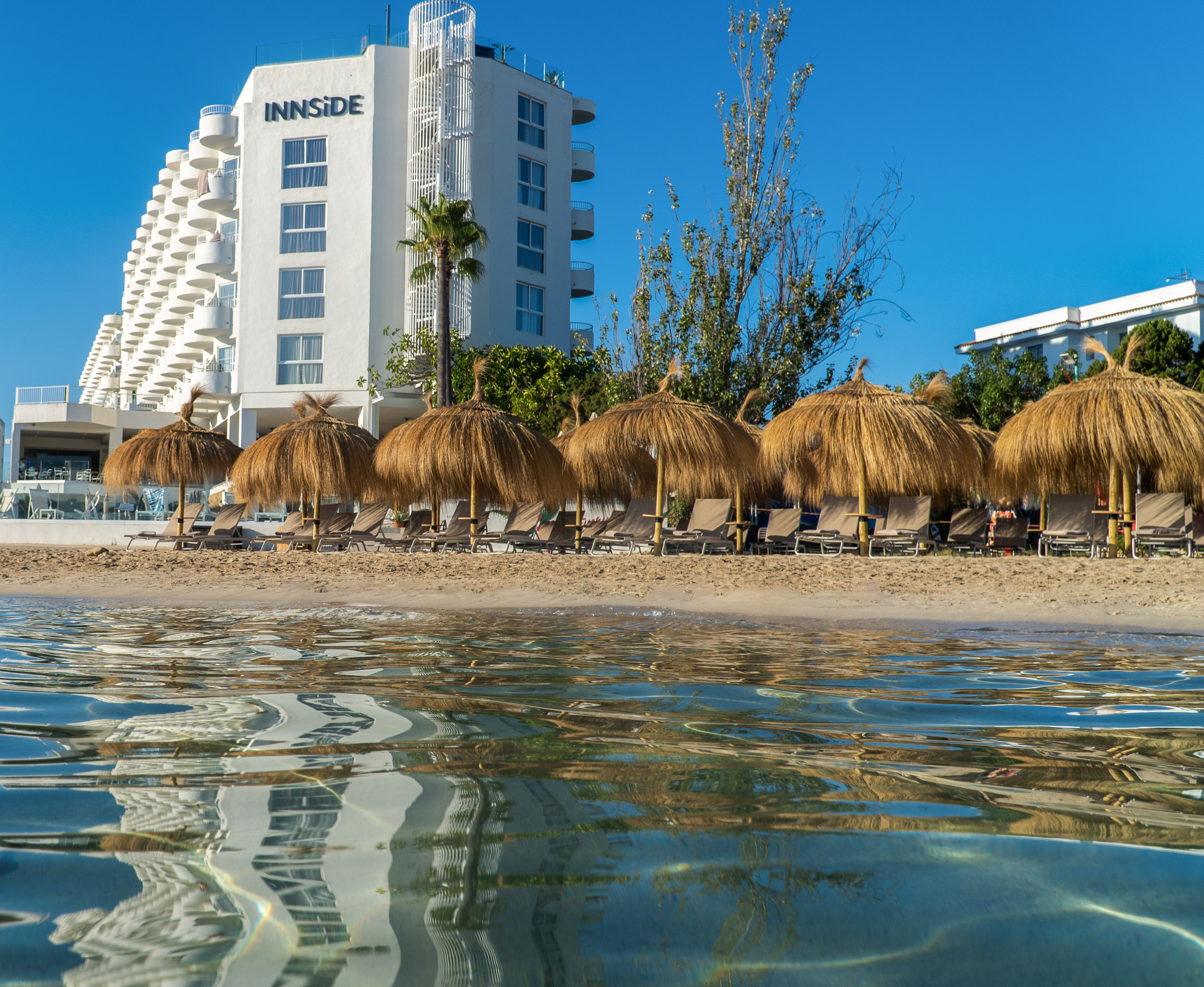 Innside beach resort hotel, straw umbrellas, lounge chairs, ocean reflections.