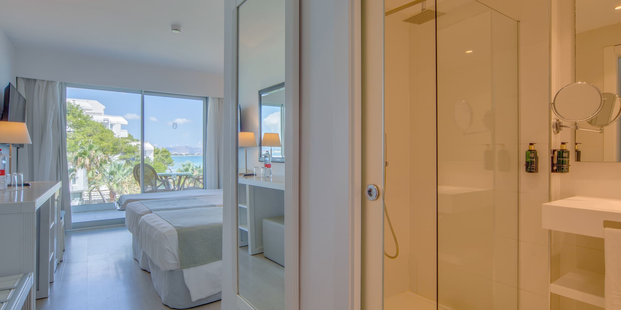 a bathroom with a glass shower and a bed