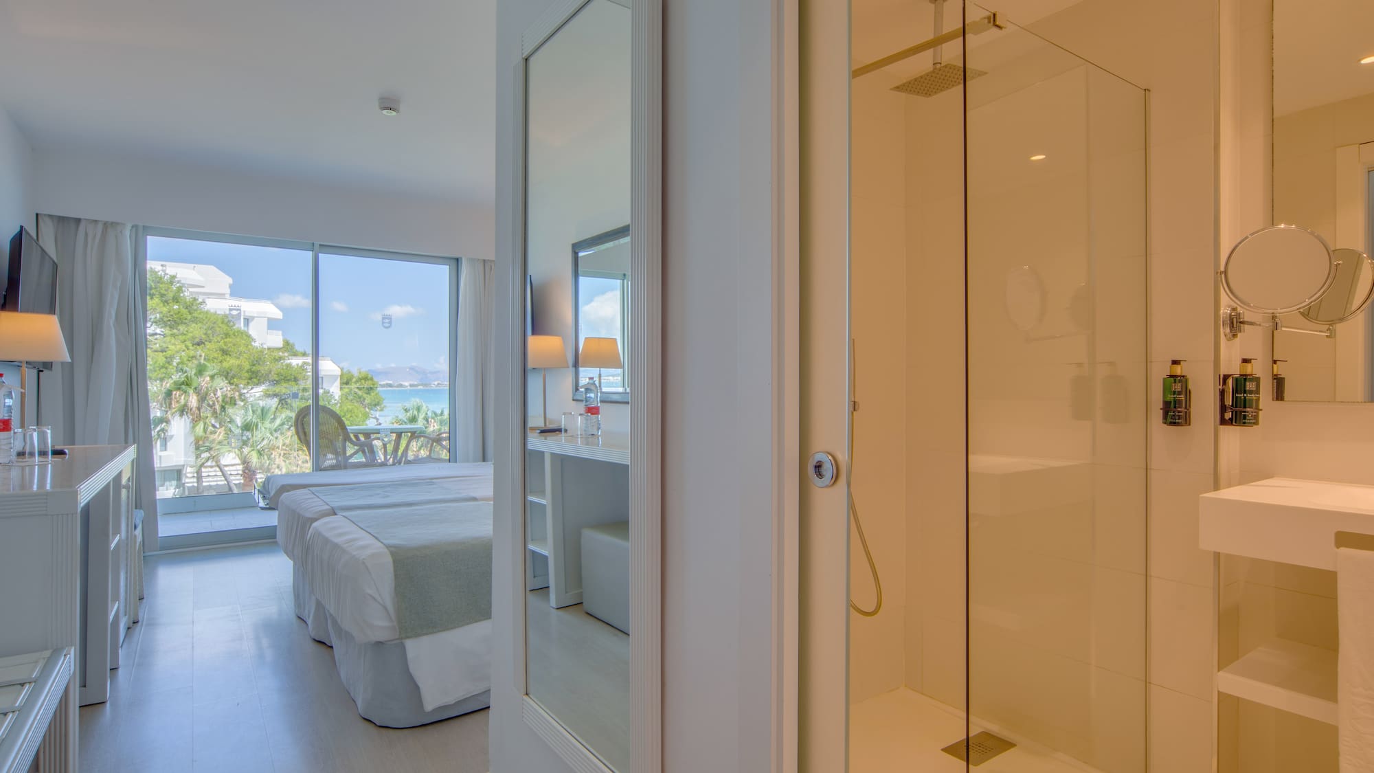 a bathroom with a glass shower and a bed