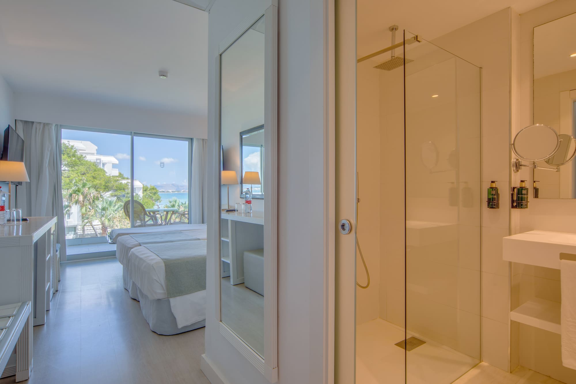 a bathroom with a glass shower and a bed