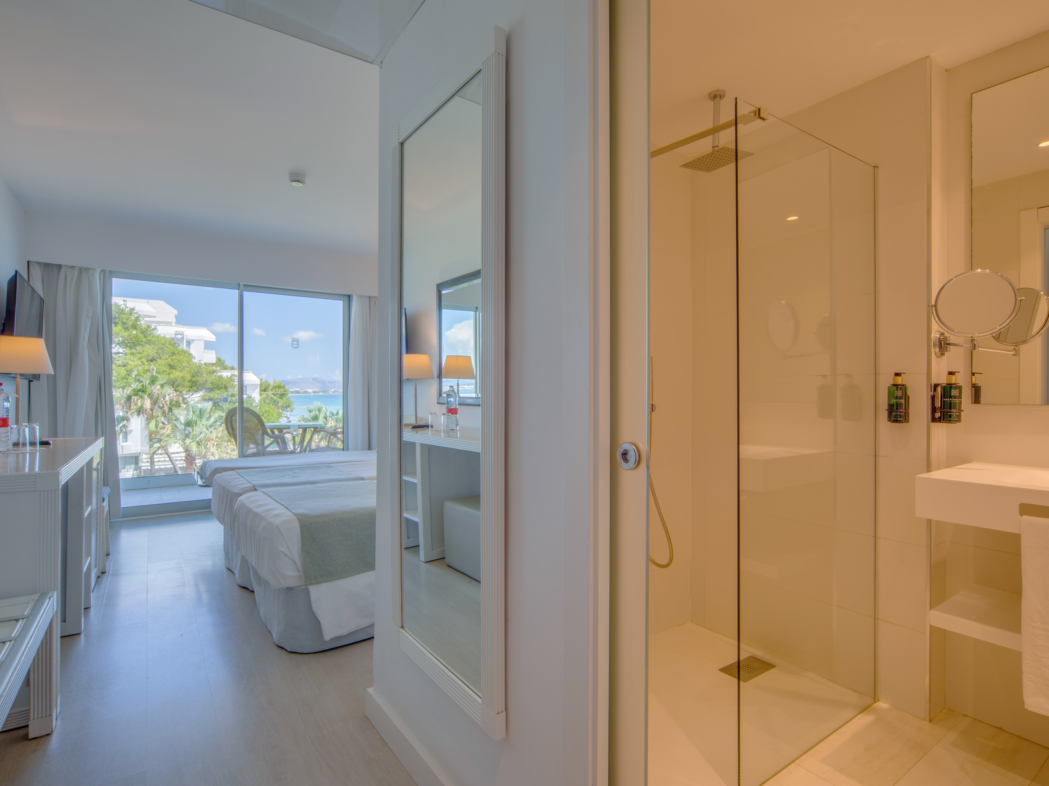 a bathroom with a glass shower and a bed