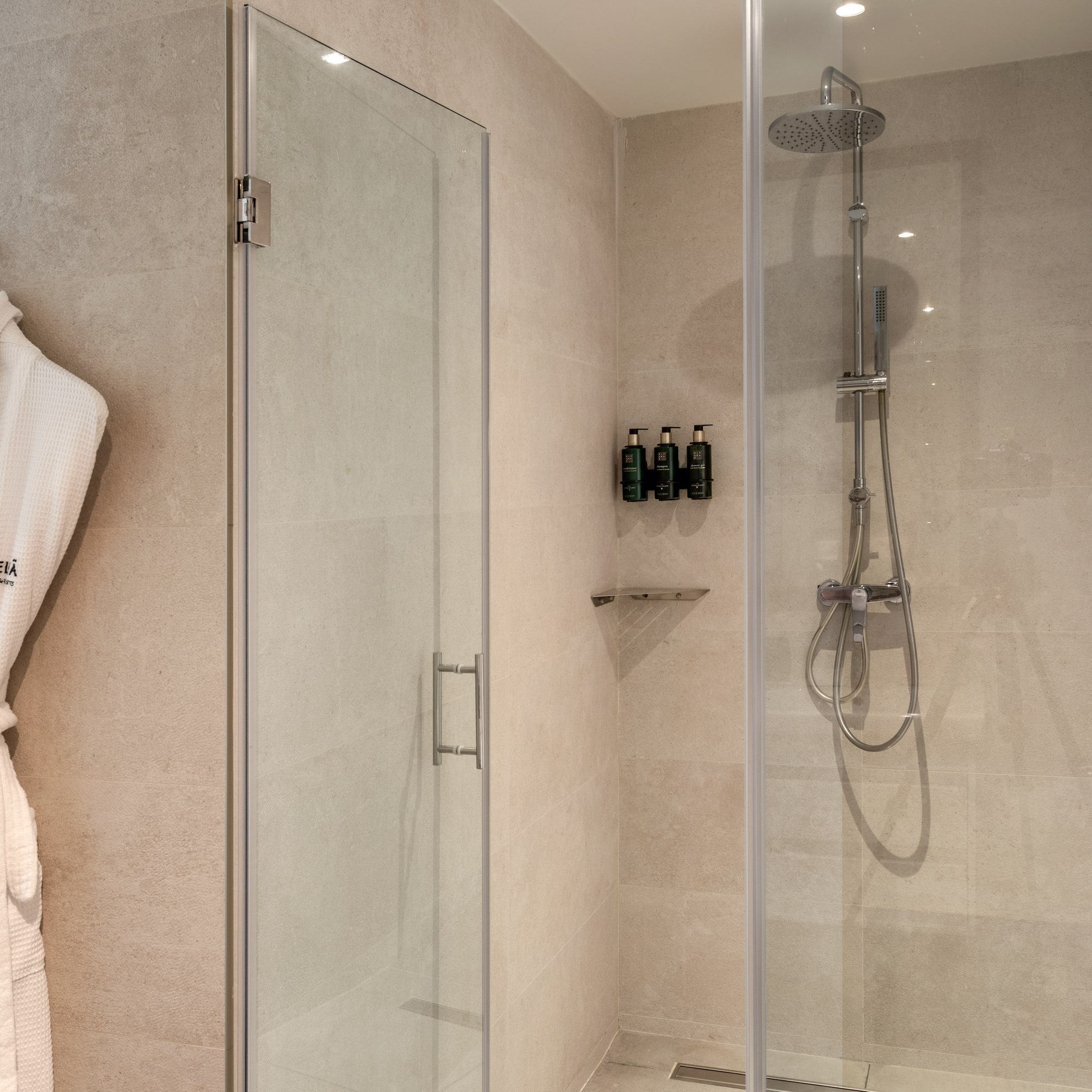 Modern hotel bathroom shower with Meliá bathrobes and amenities.