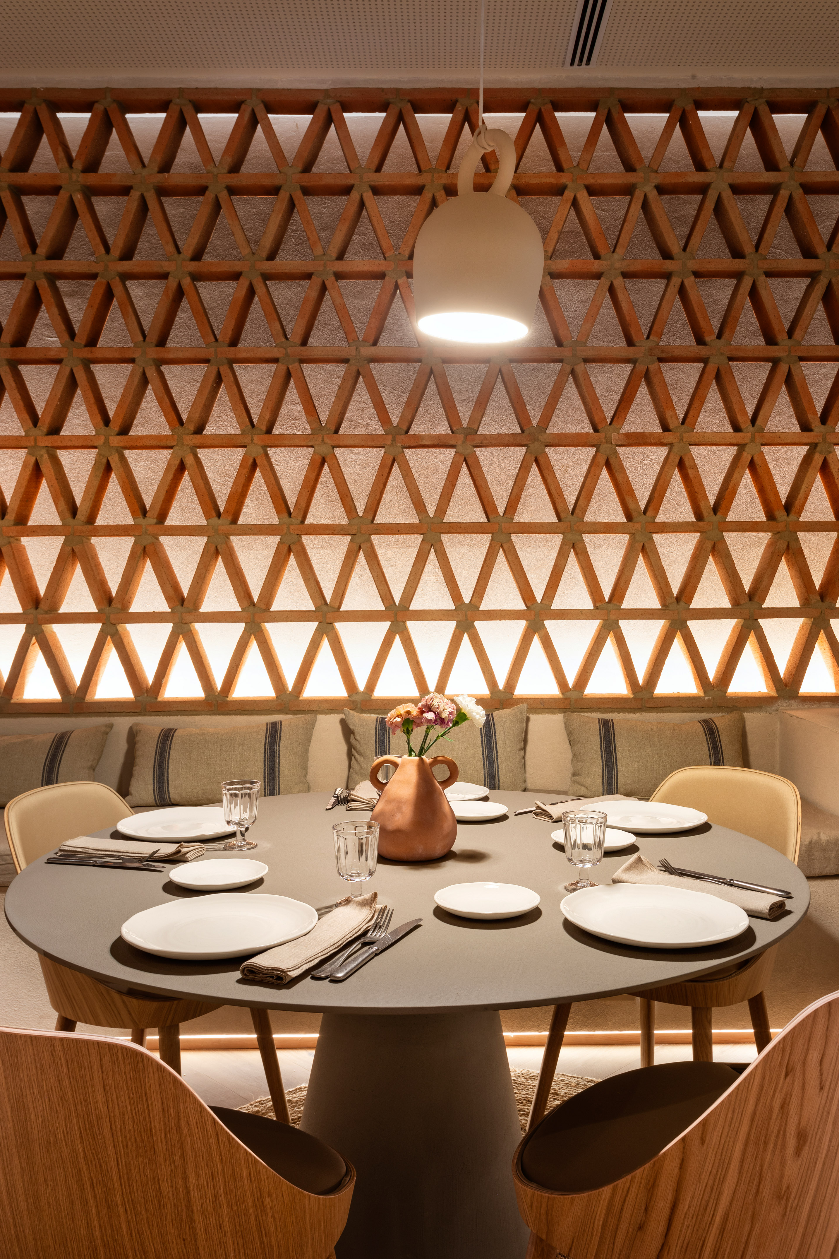 Modern restaurant interior with set dining table and terracotta triangular wall.