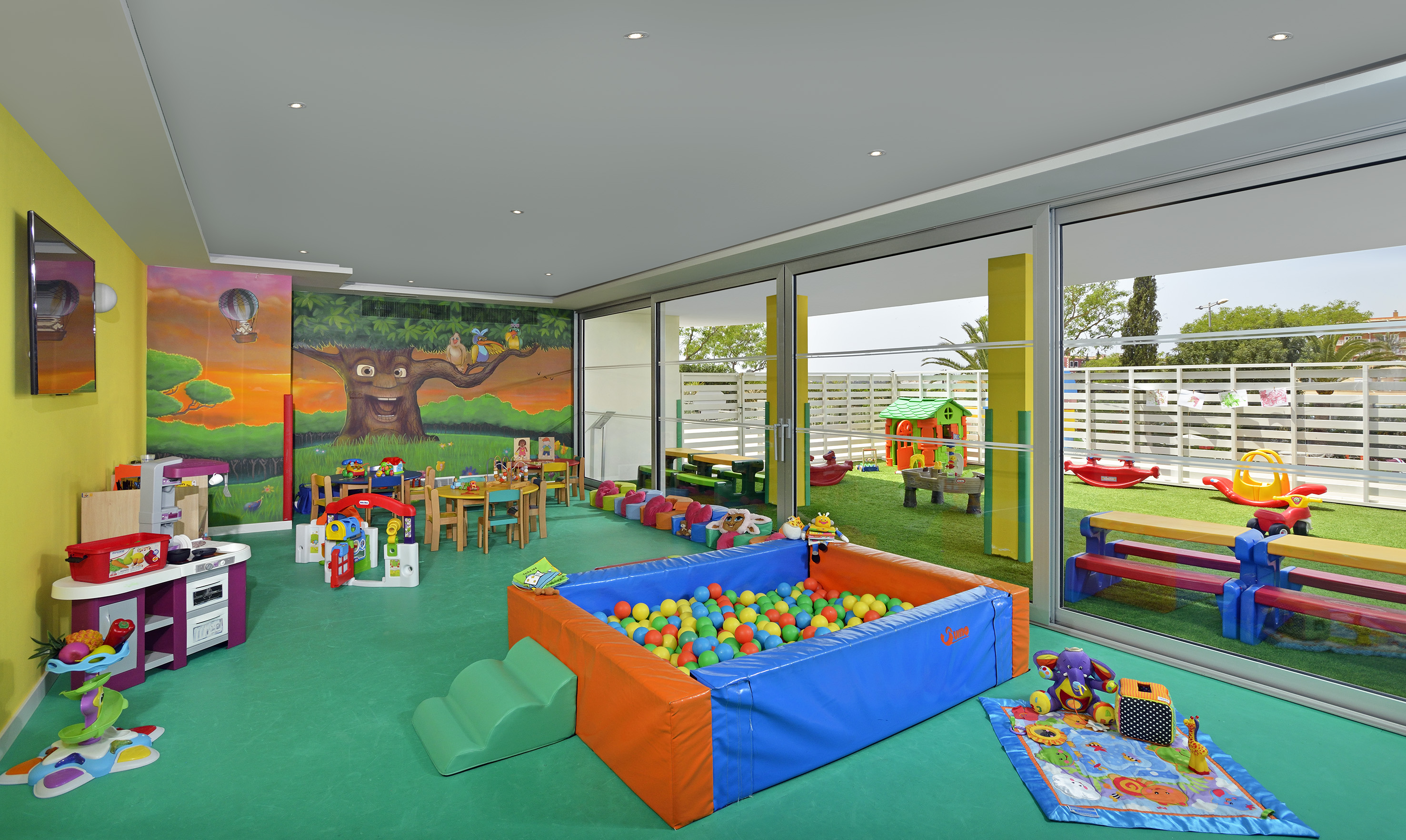 Colorful kids play area with ball pit, murals, and outdoor playground access.