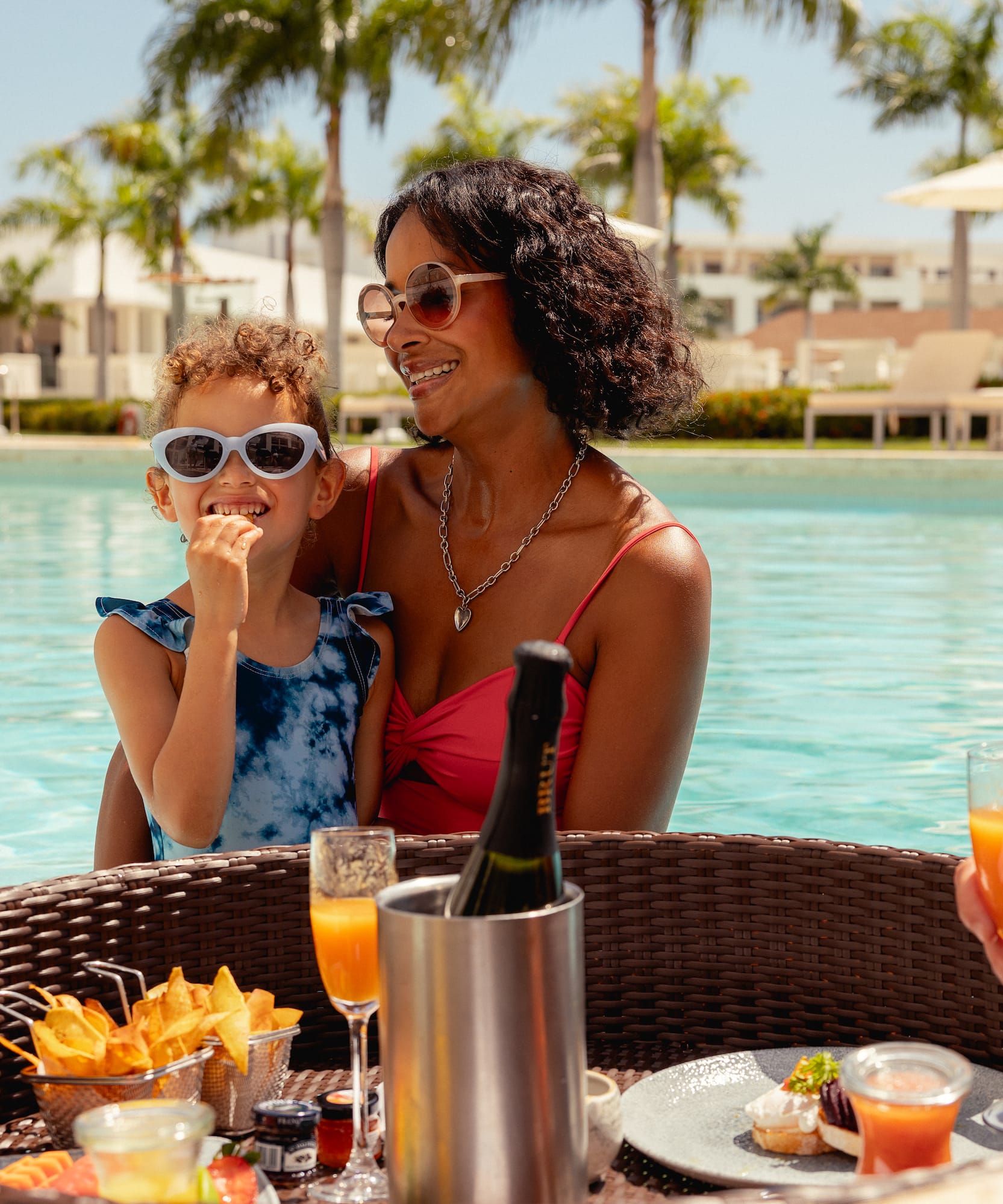 Happy mom and child enjoying floating breakfast in a tropical resort pool.