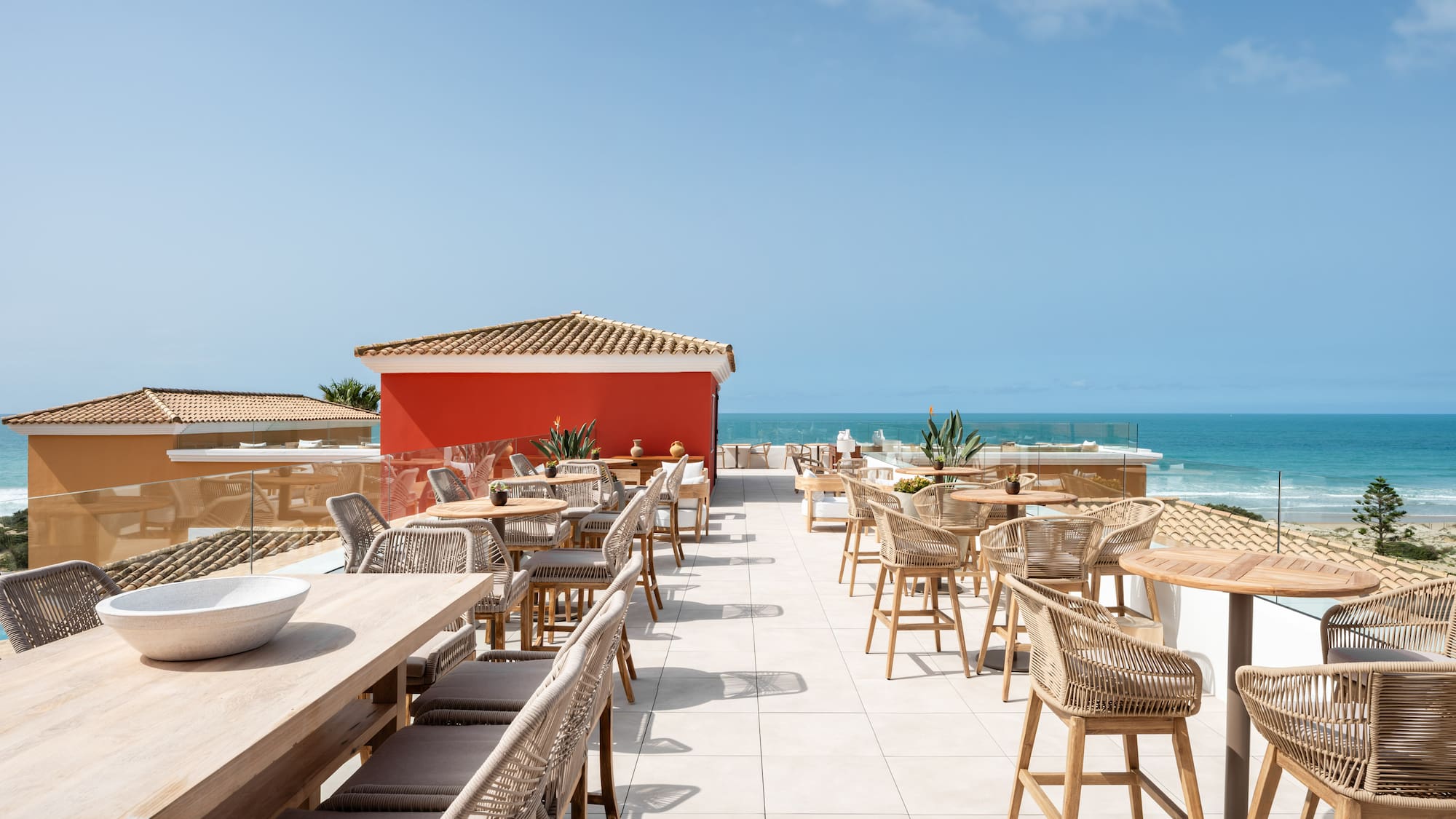 a restaurant with tables and chairs on a rooftop overlooking the ocean