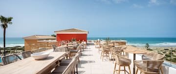 a restaurant with tables and chairs on a rooftop overlooking the ocean