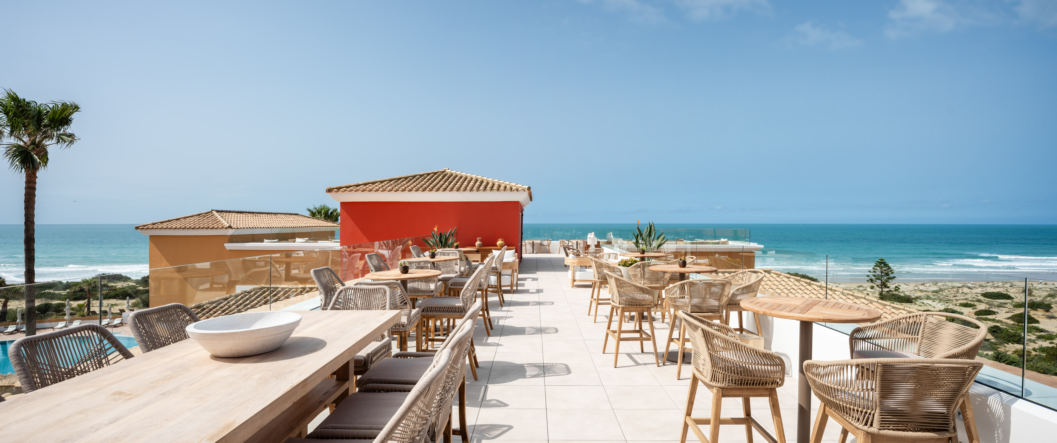 a restaurant with tables and chairs on a rooftop overlooking the ocean