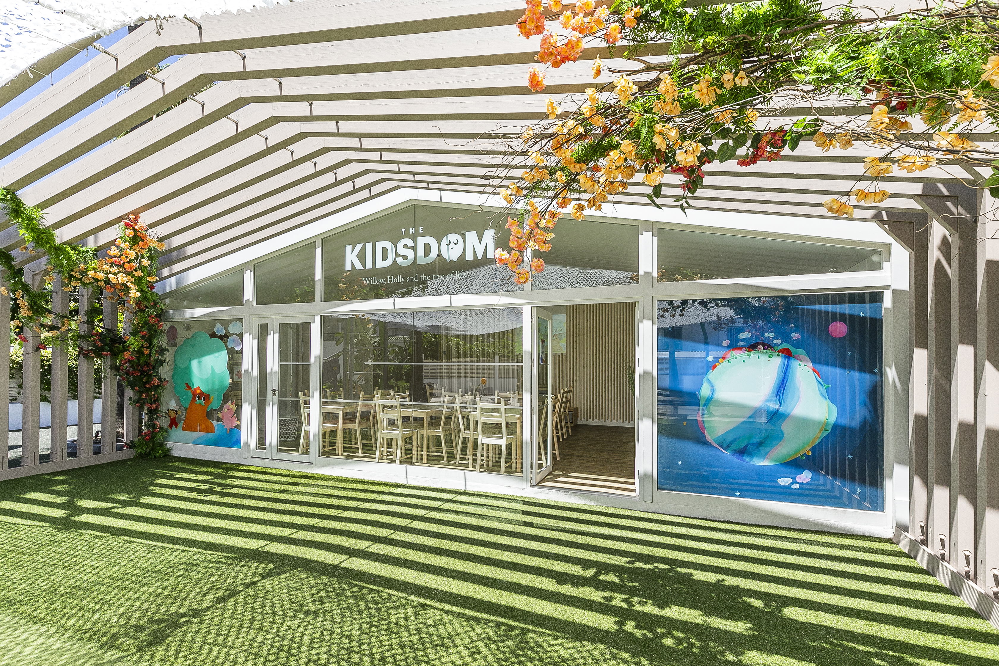 Kidsdom children's center, outdoor turf, pergola, and colorful window art.