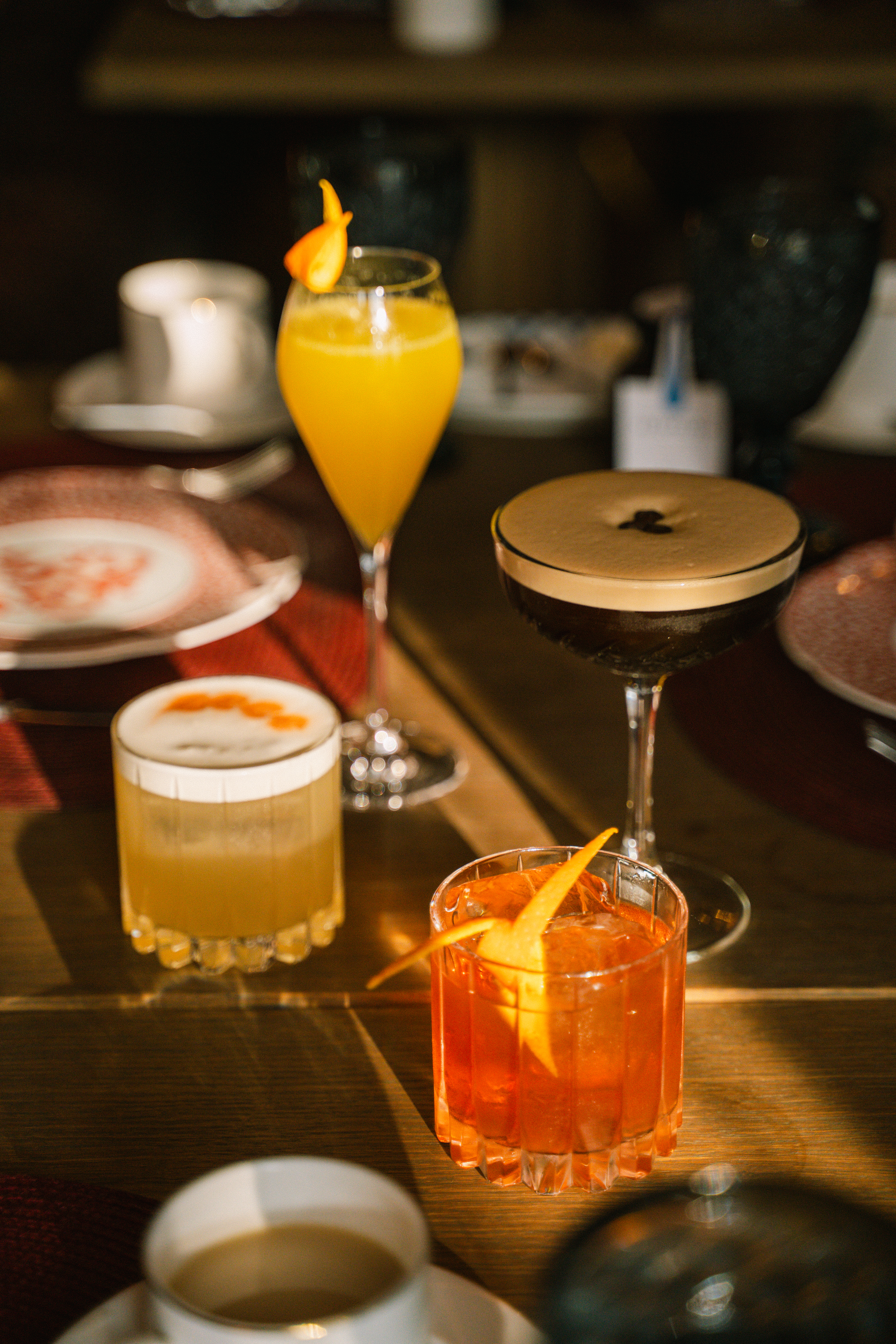 Assorted cocktails: espresso martini, mimosa, and citrus drinks on a wooden table.