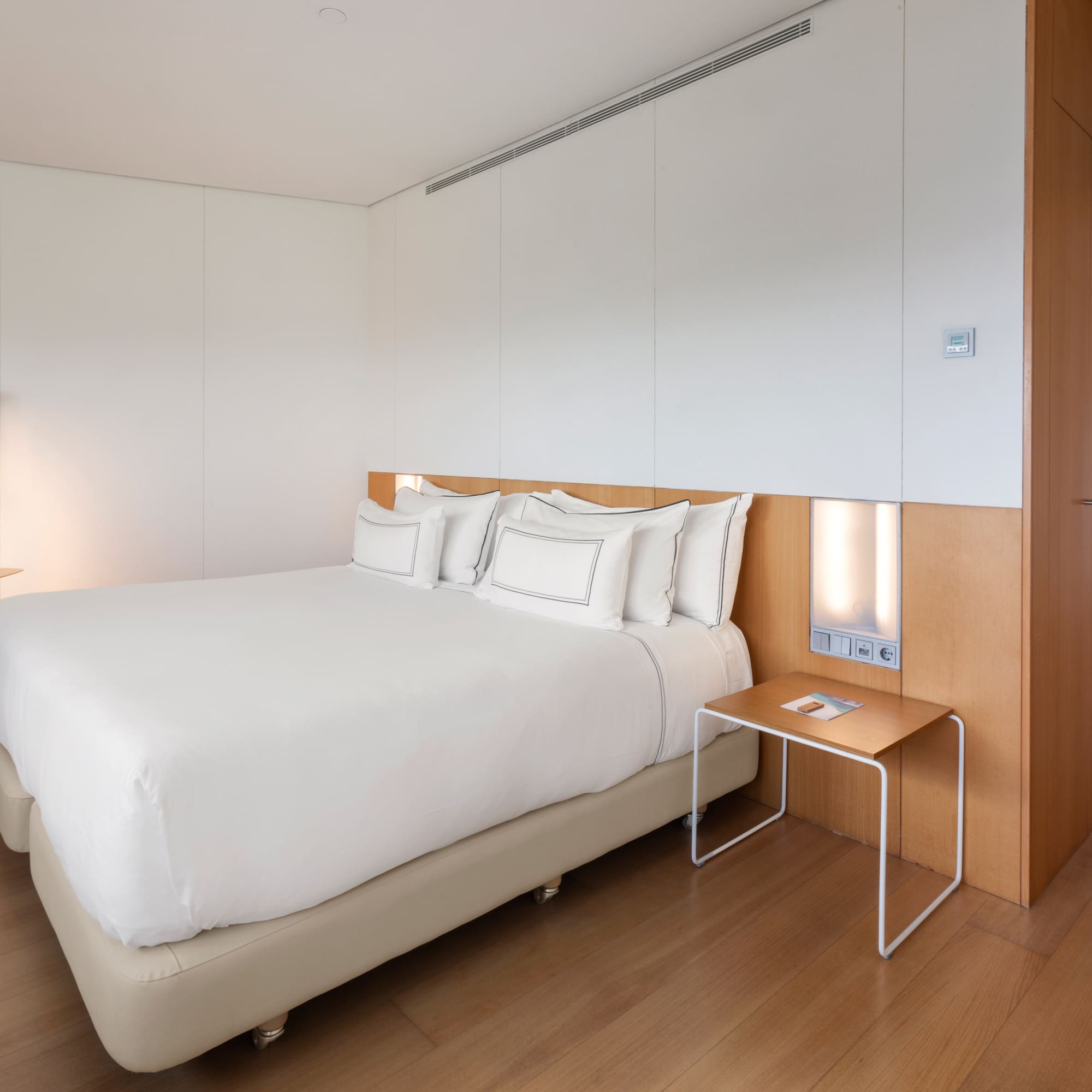 a bed with white sheets and a table