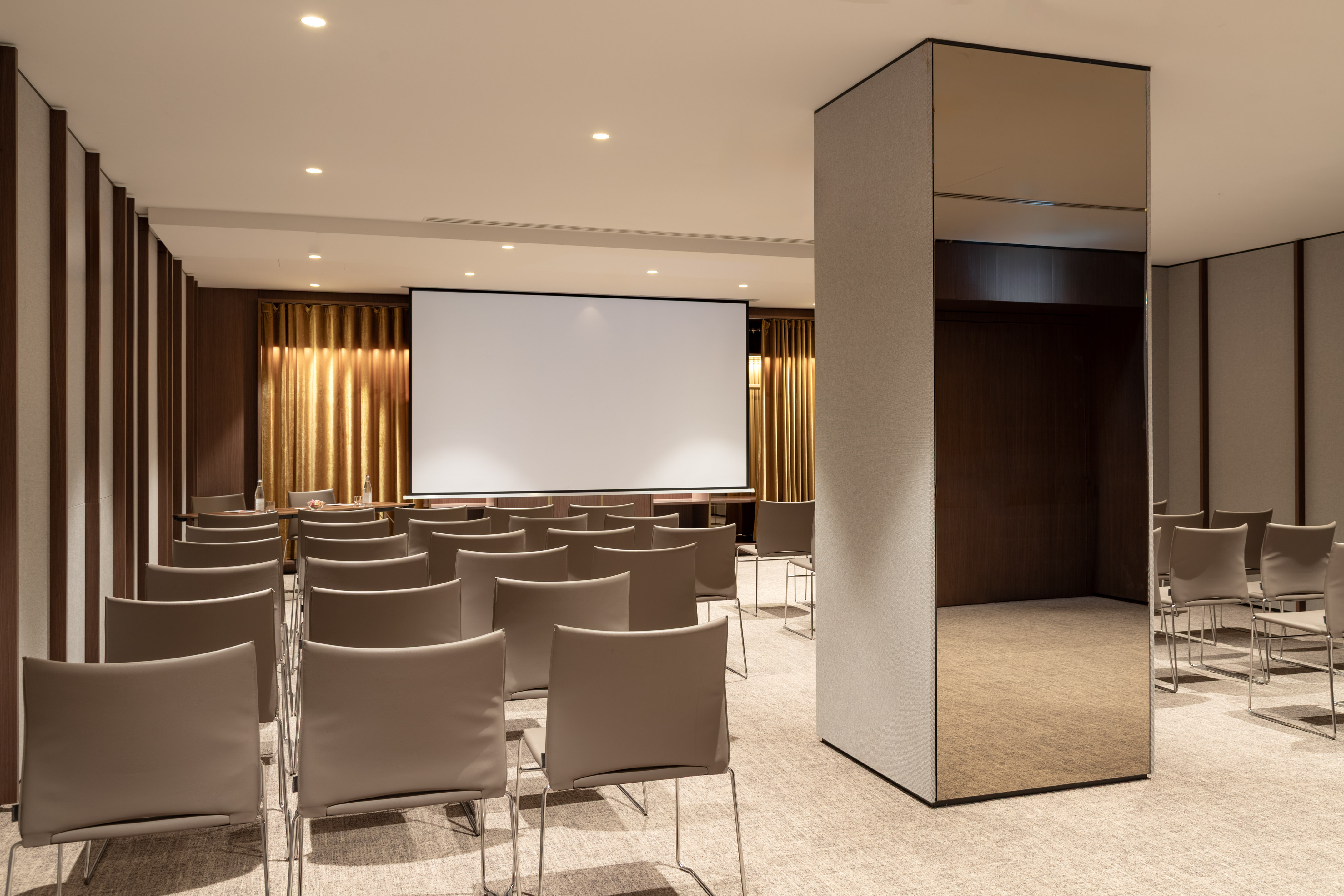 Modern conference room with projector screen and rows of chairs for events.