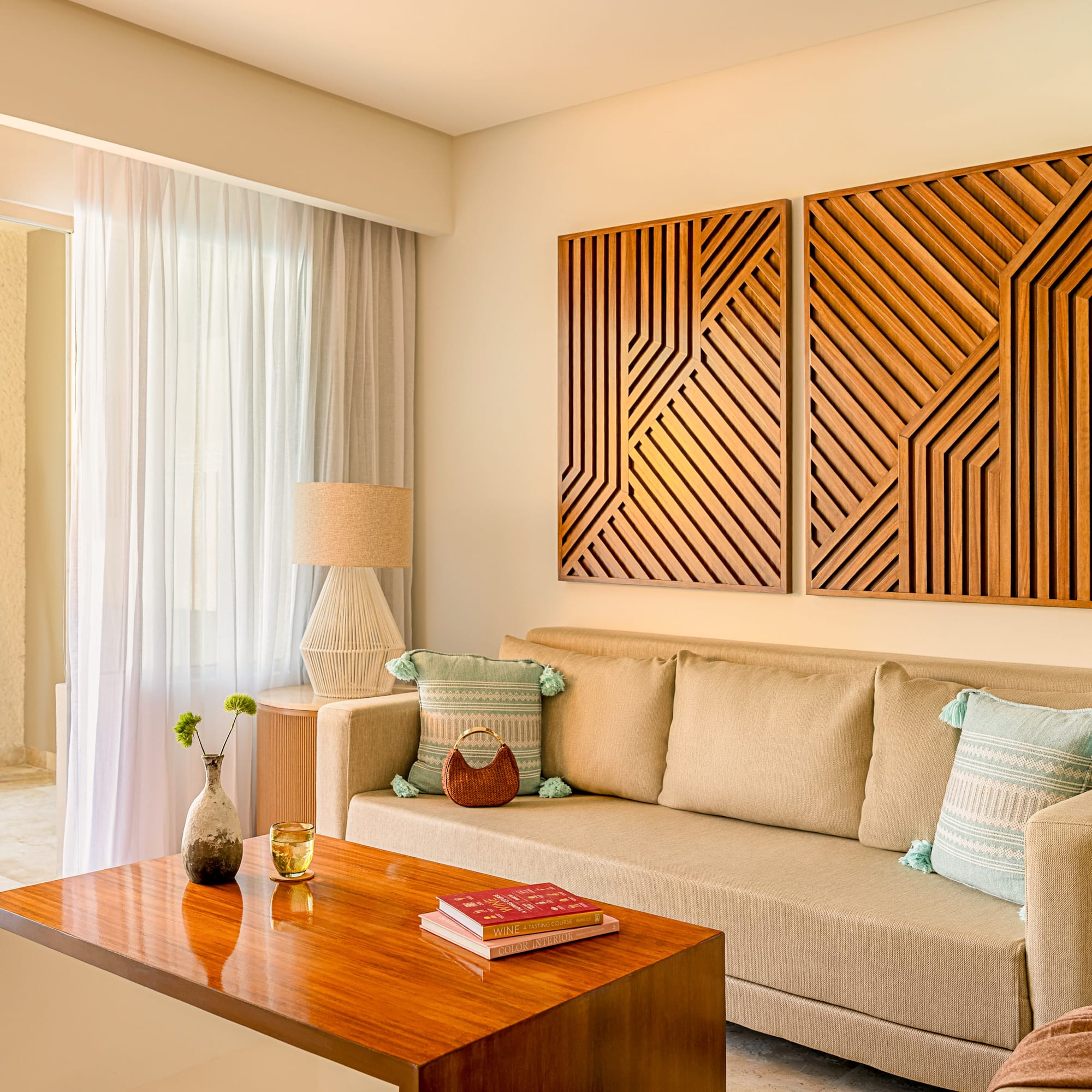 Resort living room with beige sofa, wood table, geometric art, and balcony.