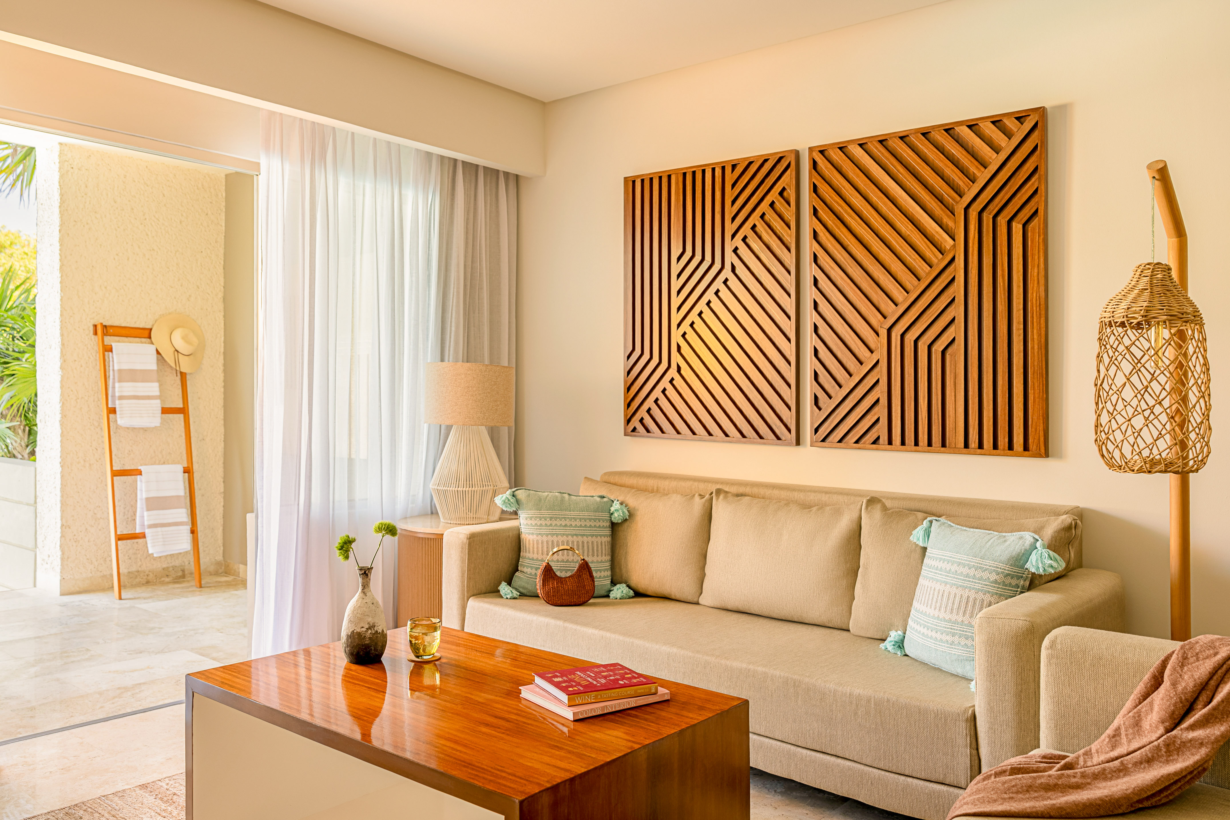 Resort living room with beige sofa, wood table, geometric art, and balcony.