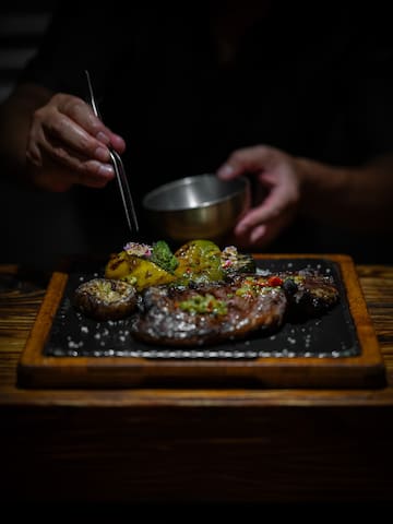 a person holding tongs to a plate of food