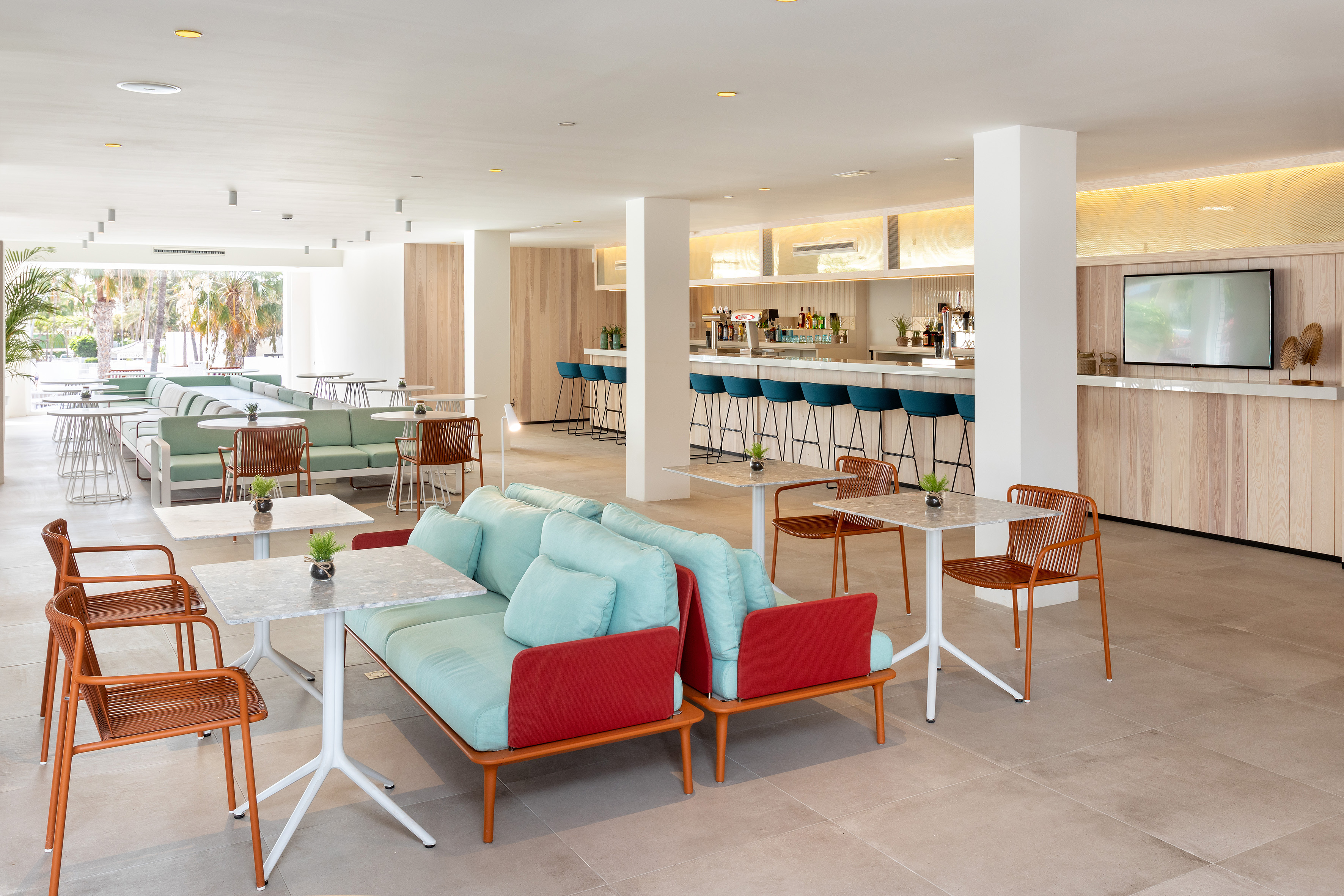 Modern hotel lounge bar with light wood, blue stools, and contemporary seating.