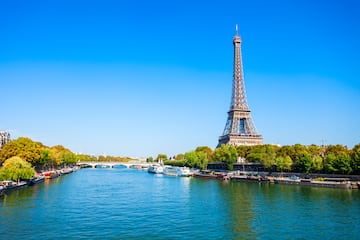 a large metal tower next to a river with Seine in the background