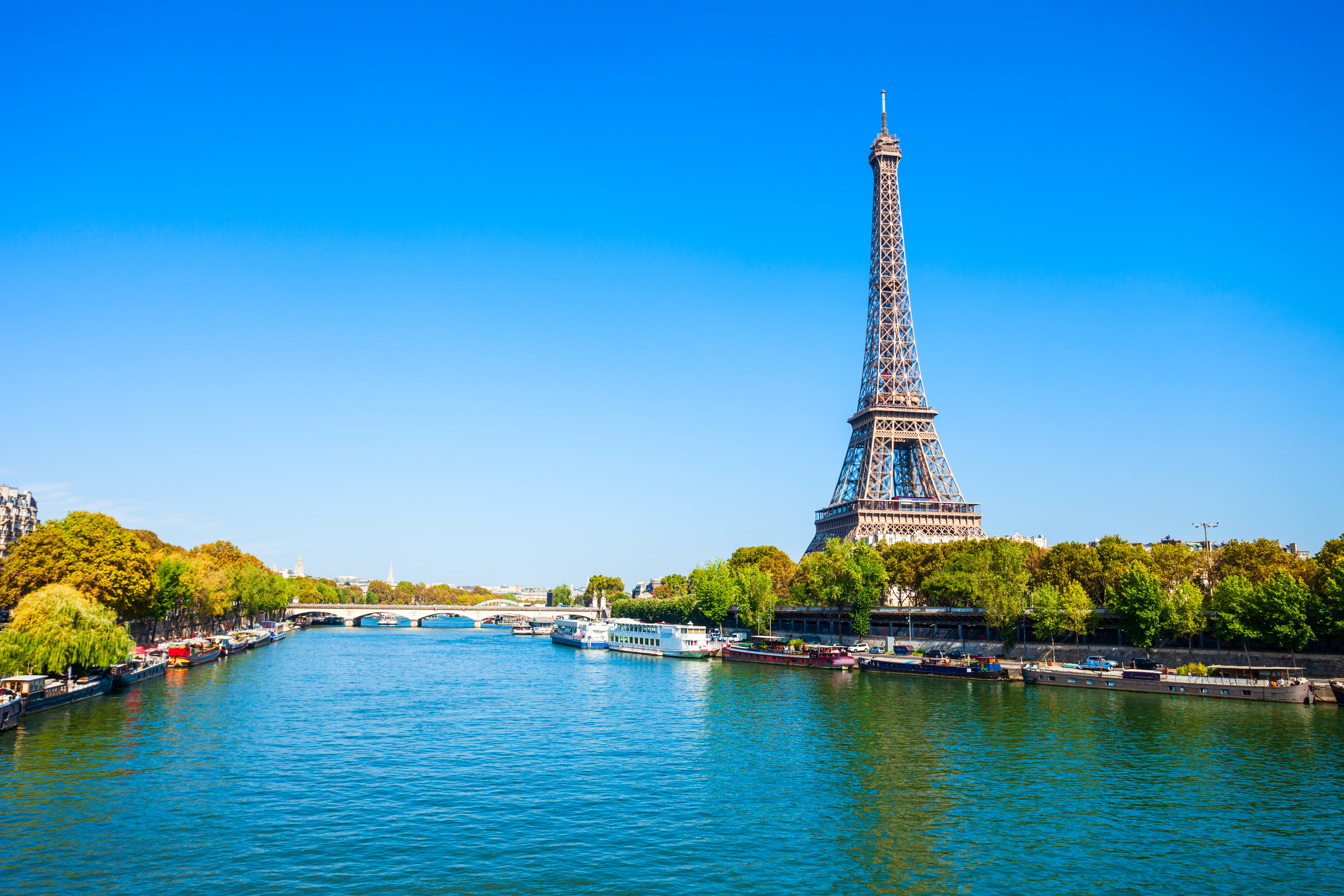 a large metal tower next to a river with Seine in the background