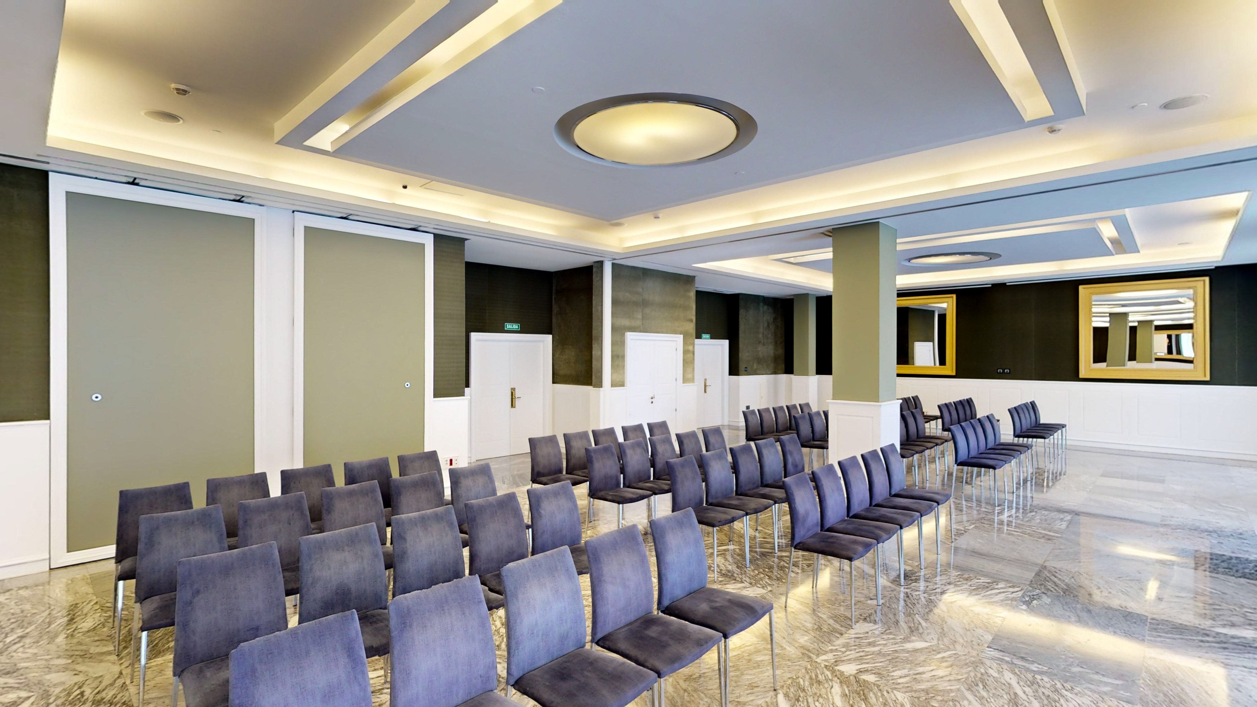 Modern conference room, blue chairs, polished marble floor, recessed lighting.