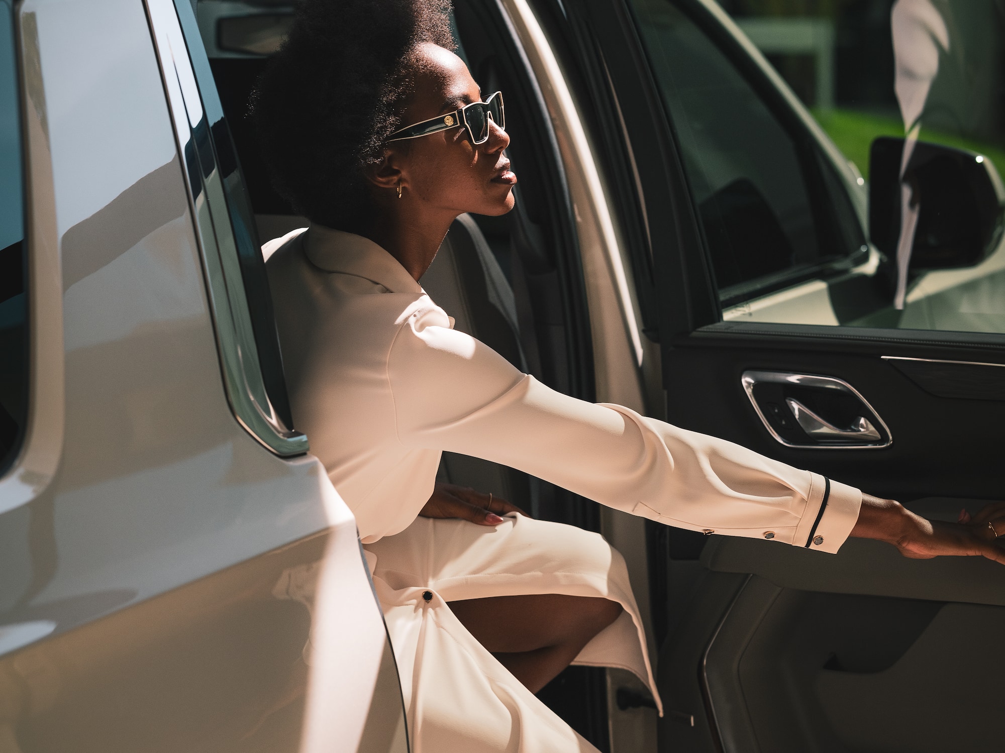 a woman in a white dress and sunglasses leaning out of a car