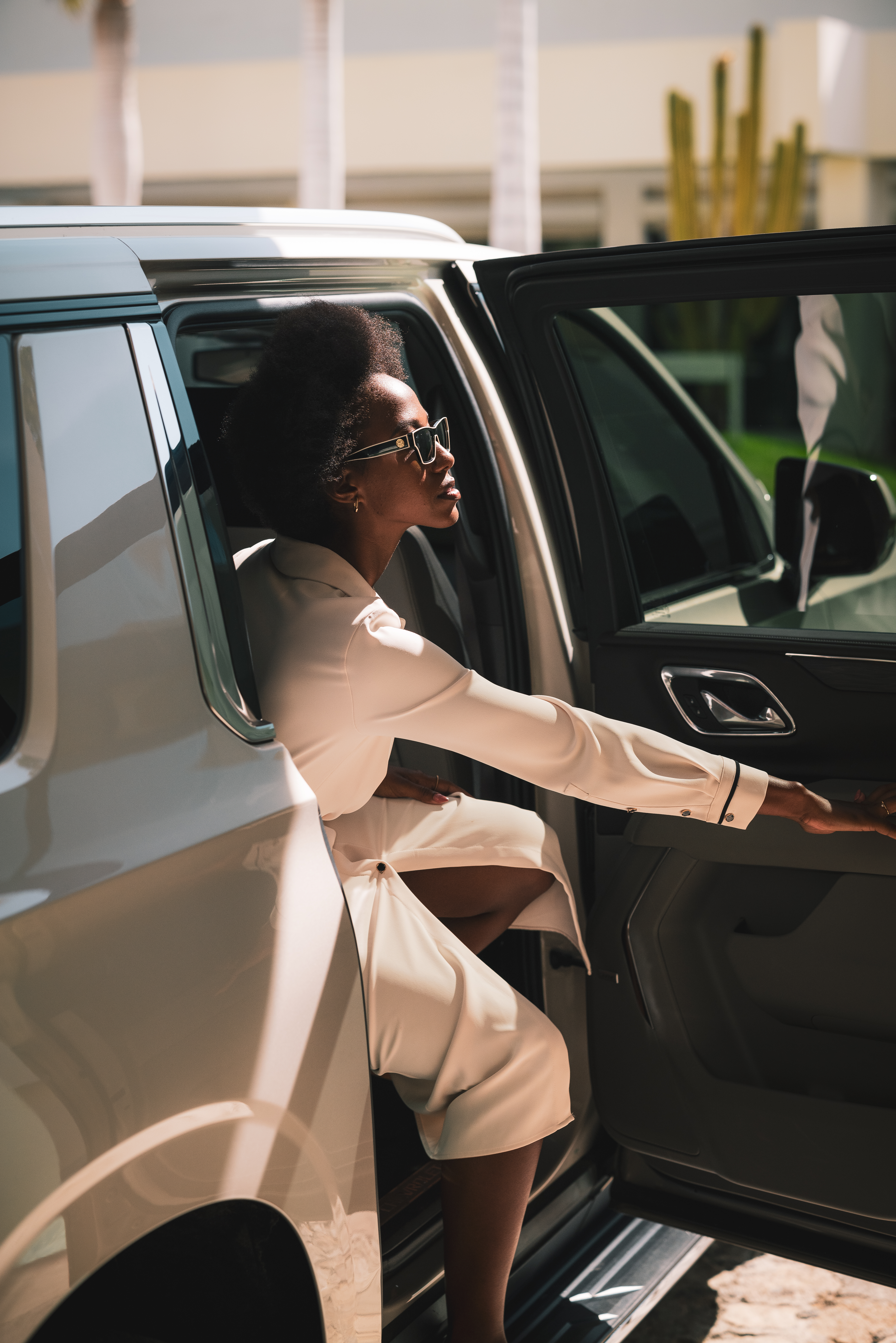 a woman in a white dress and sunglasses leaning out of a car