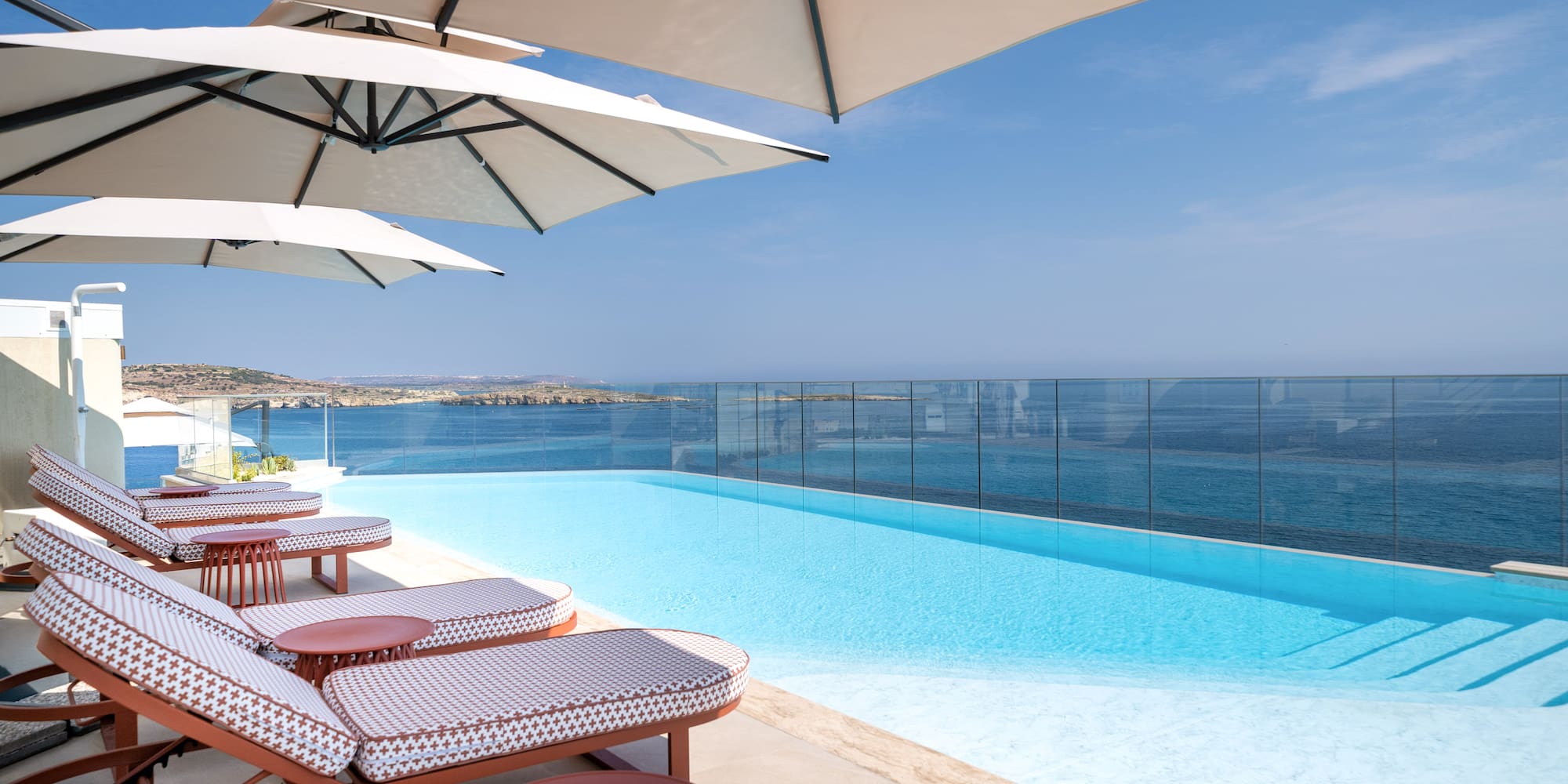 Resort infinity pool, sun loungers, umbrellas, and vast ocean view.