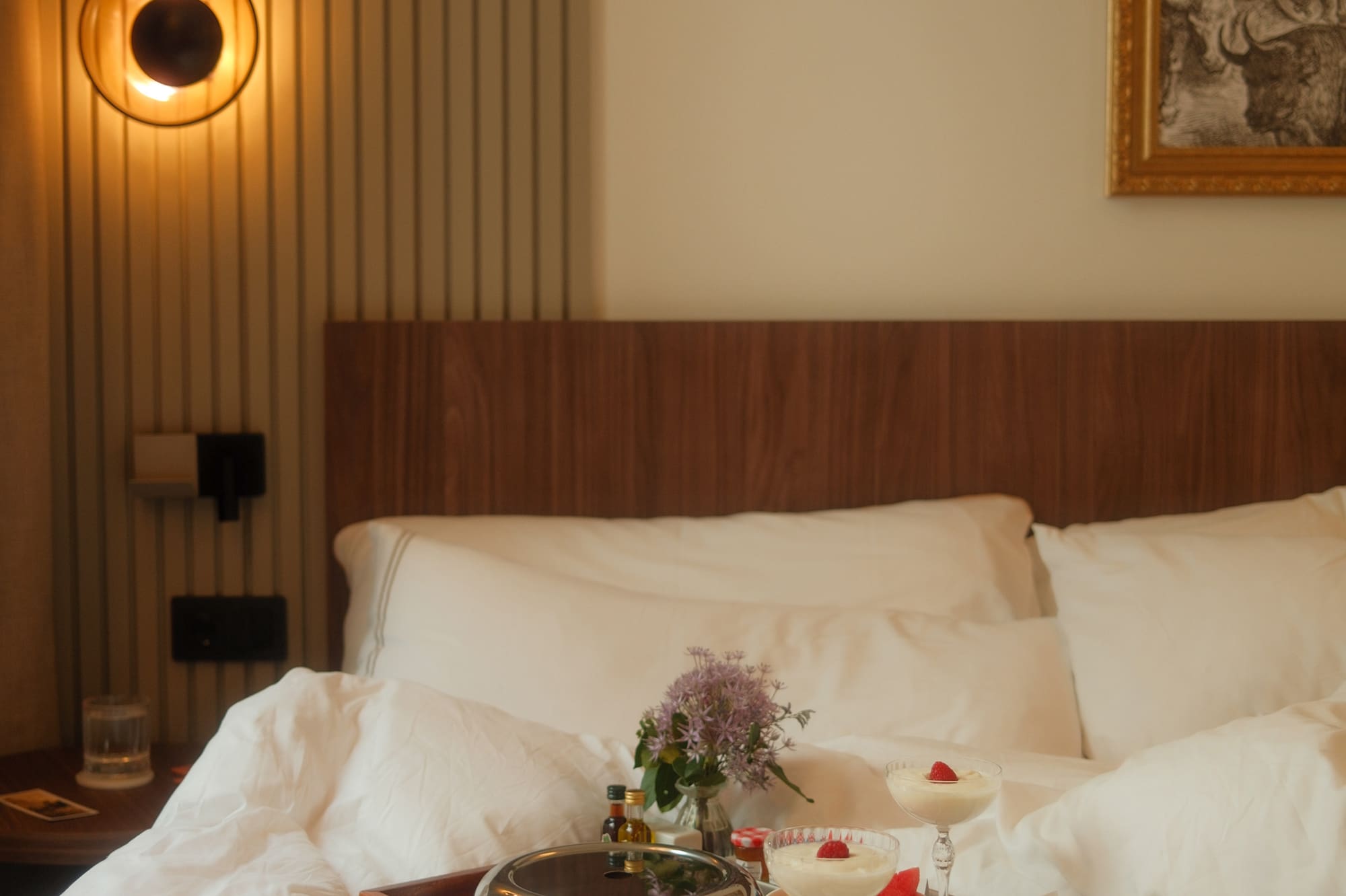 Cozy hotel room with room service breakfast in bed: coffee, fruit, dessert.
