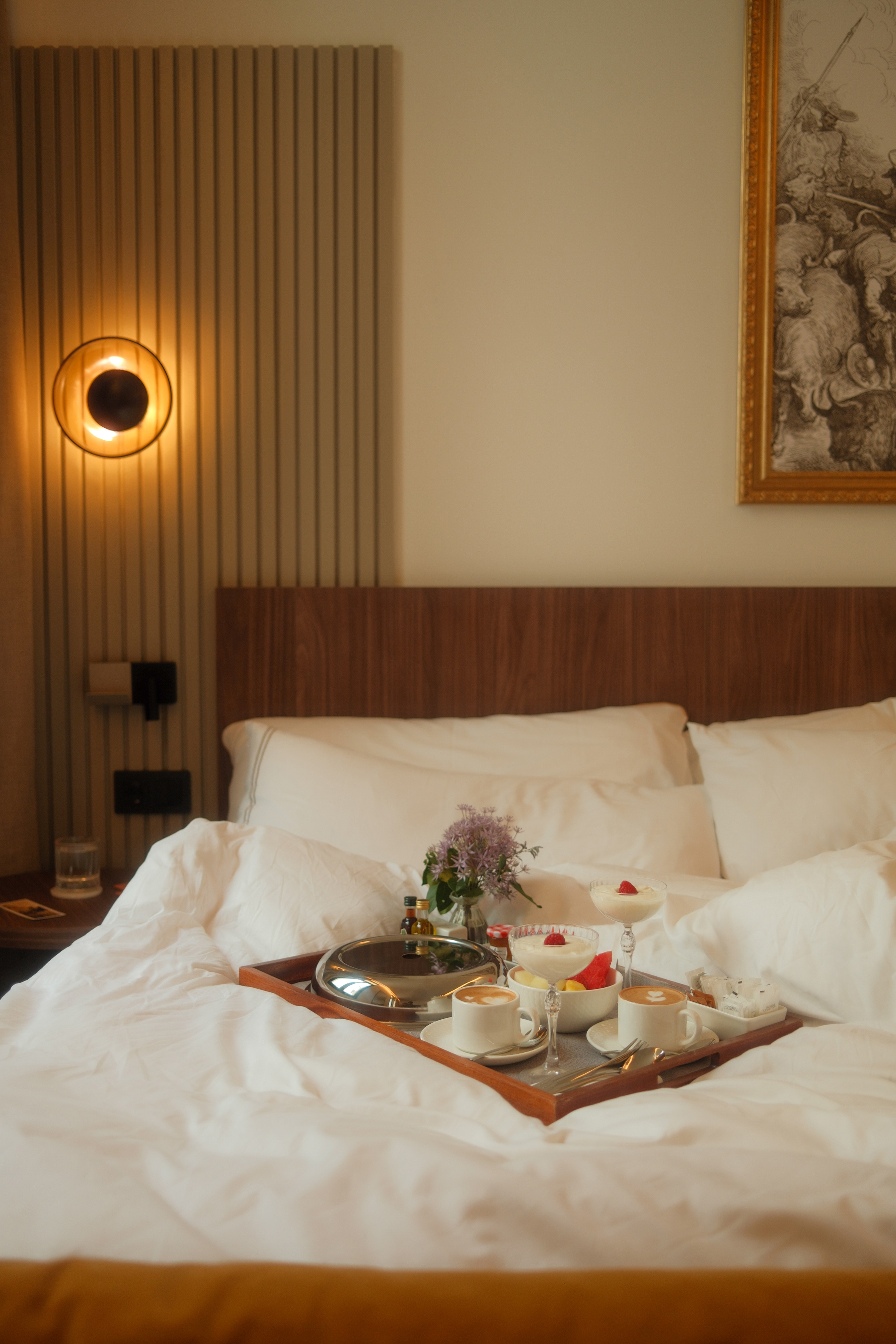 Cozy hotel room with room service breakfast in bed: coffee, fruit, dessert.