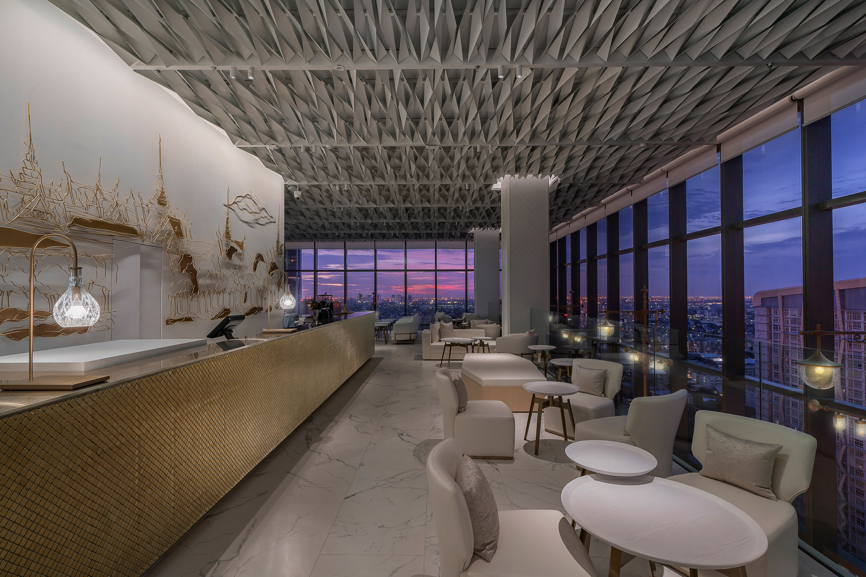 Rooftop bar with modern interior, sunset city view, and golden Thai wall art.