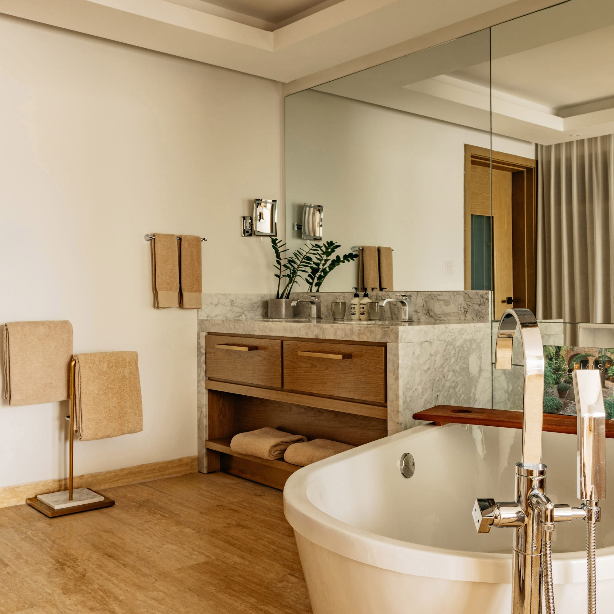 Modern bathroom with freestanding tub, marble vanity, and warm wood accents.