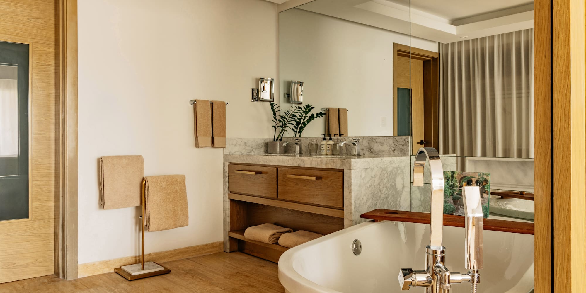 Modern bathroom with freestanding tub, marble vanity, and warm wood accents.