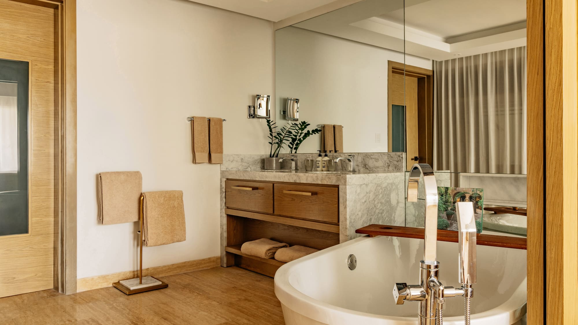Modern bathroom with freestanding tub, marble vanity, and warm wood accents.